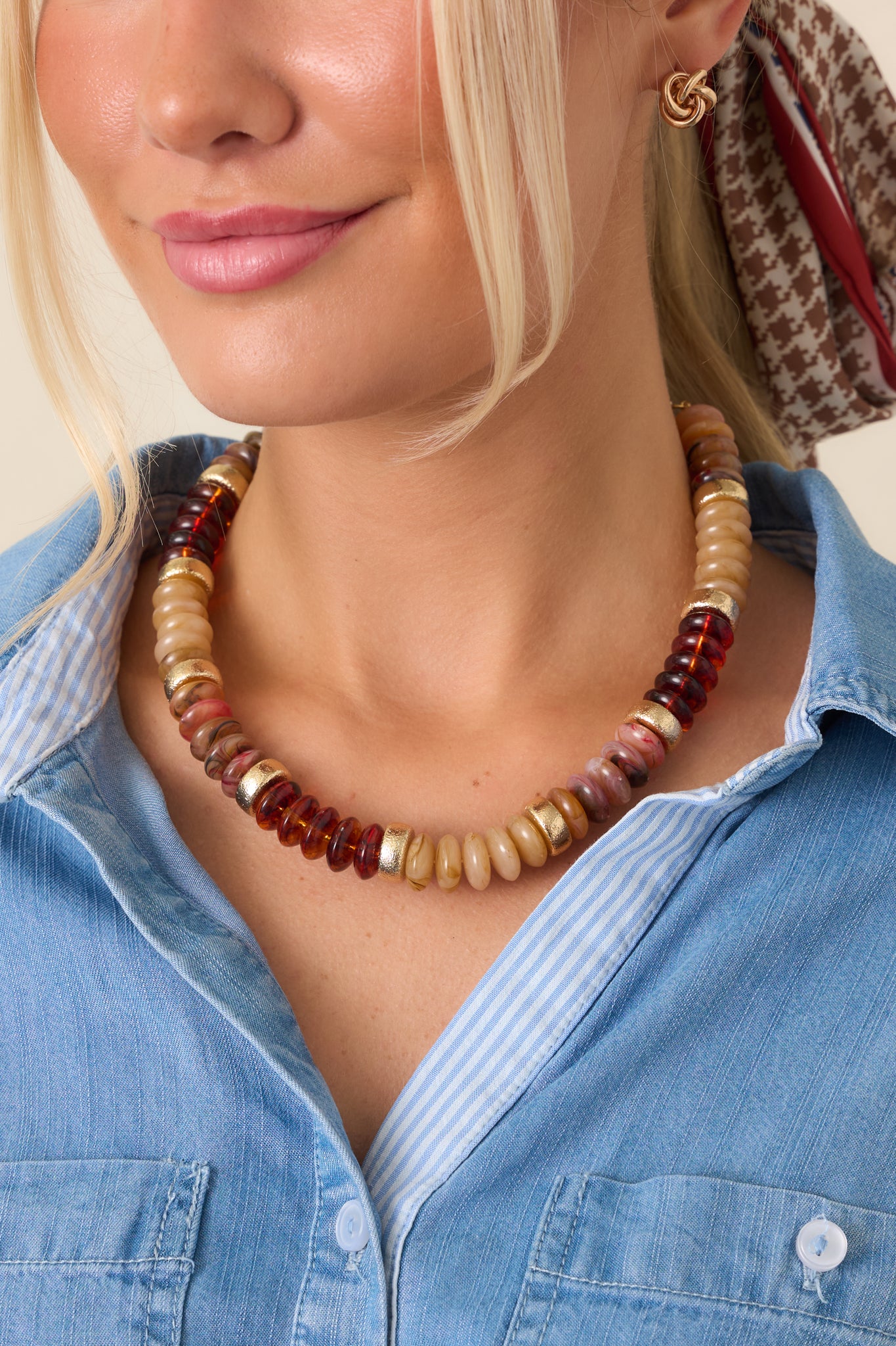 Multicolored beaded necklace featuring translucent dark brown, caramel, cream, and marbled disc beads with textured gold-tone accents.