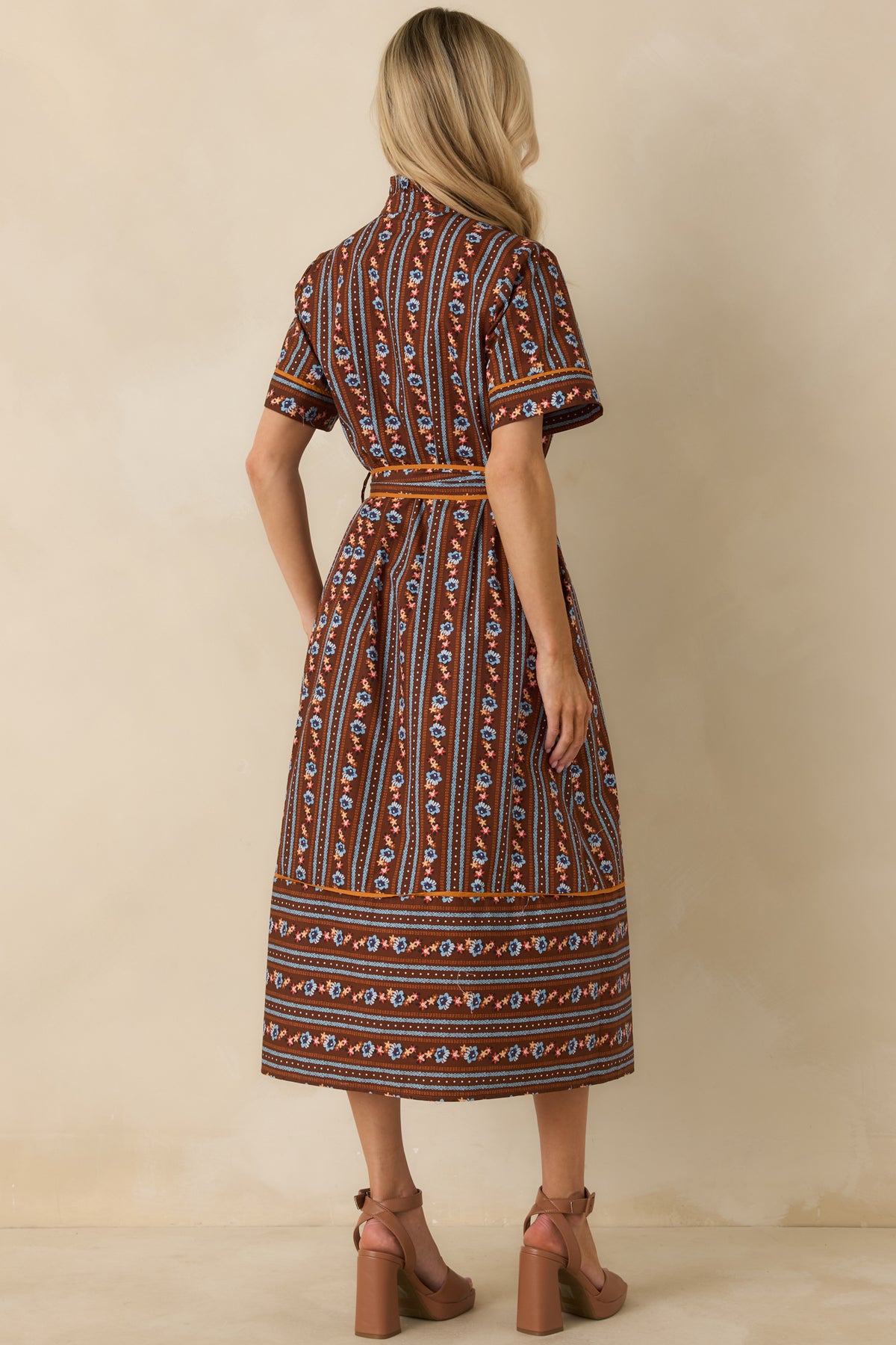 Rear view of the brown cotton dress featuring alternating blue, orange, ivory, and rust patterned stripes with an A-line silhouette.