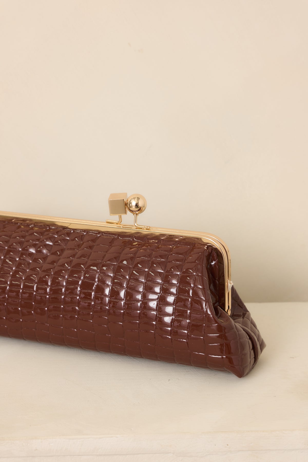 Close-up of the clutch’s croc-embossed faux leather texture and gold-tone kiss-lock frame closure, showcasing the contrasting finishes.