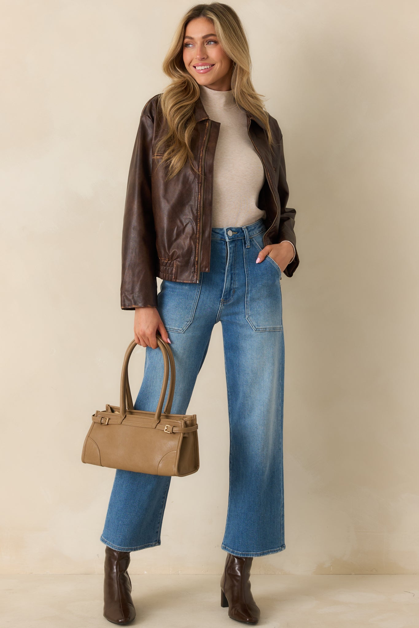 Brown faux distressed leather jacket showing its front zip and relaxed shape.