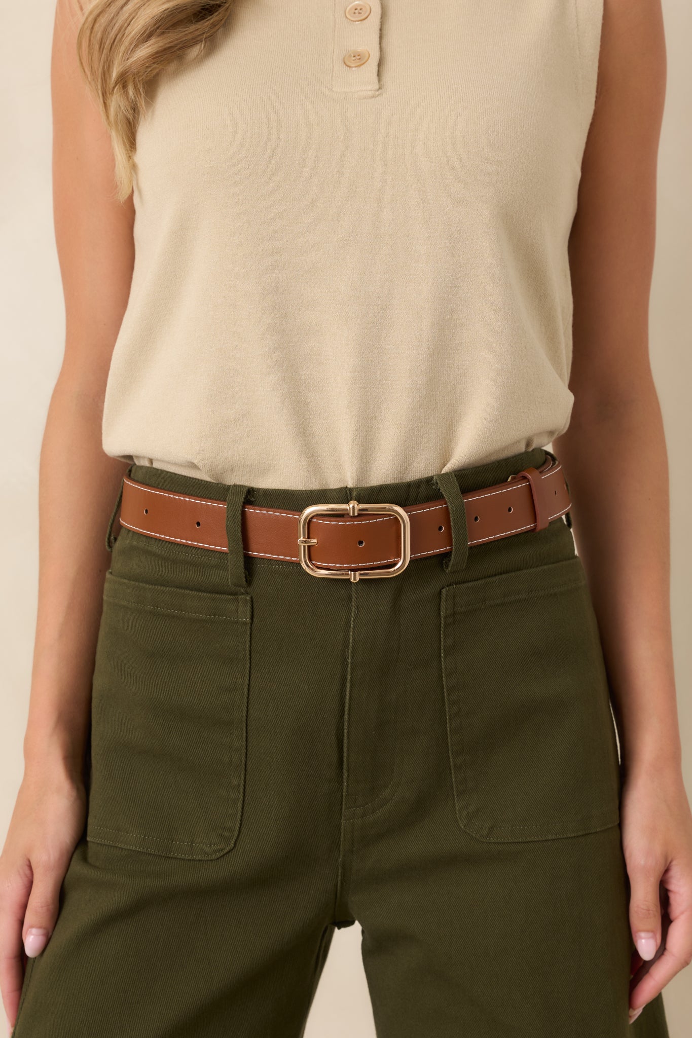 Brown faux leather belt featuring an ivory stitched border, a gold square pin buckle, and an adjustable fit.