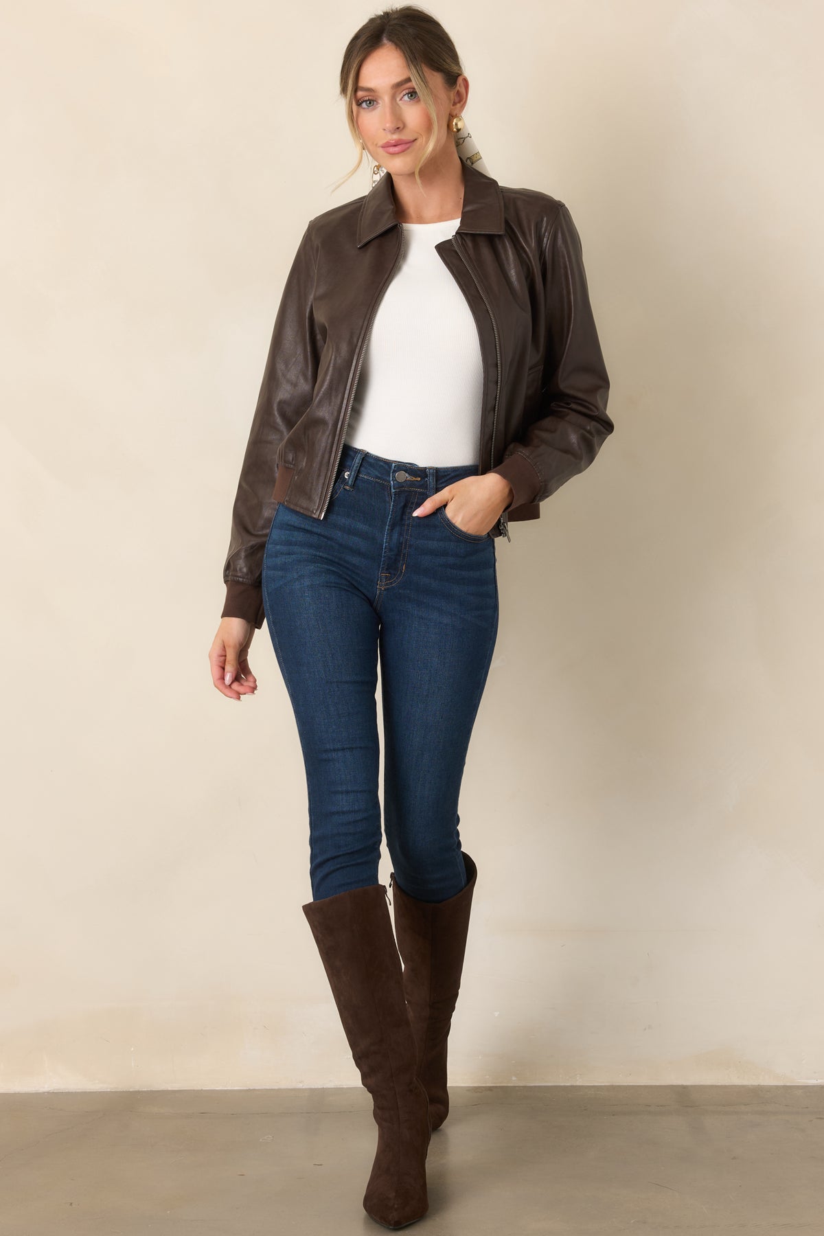 Brown faux leather bomber jacket with a classic collar, smooth zip-front design, welt pockets, ribbed cuffs, and a gently gathered hem.