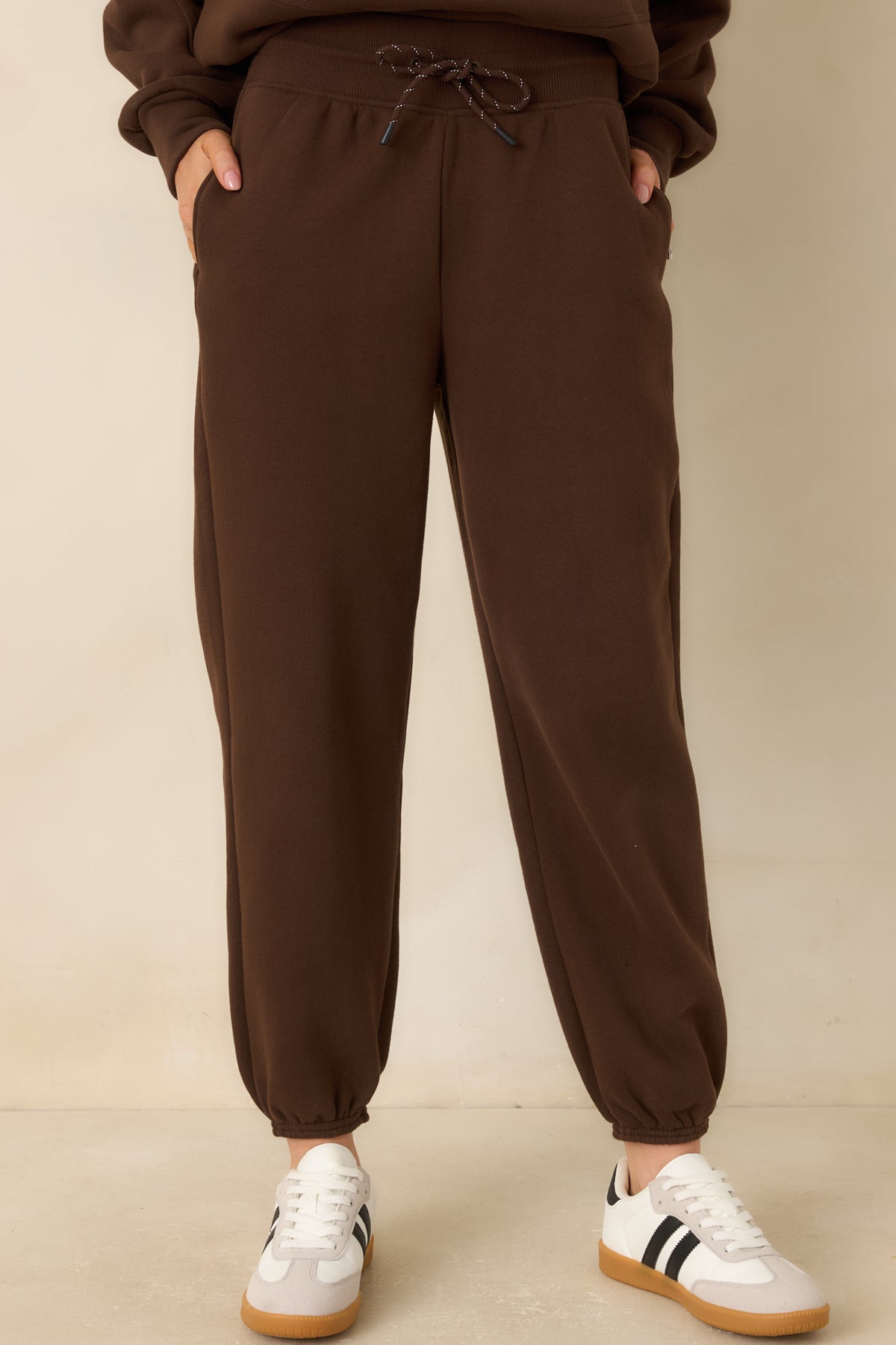 Brown fleece joggers with side pockets and a relaxed fit through the hips and thighs.