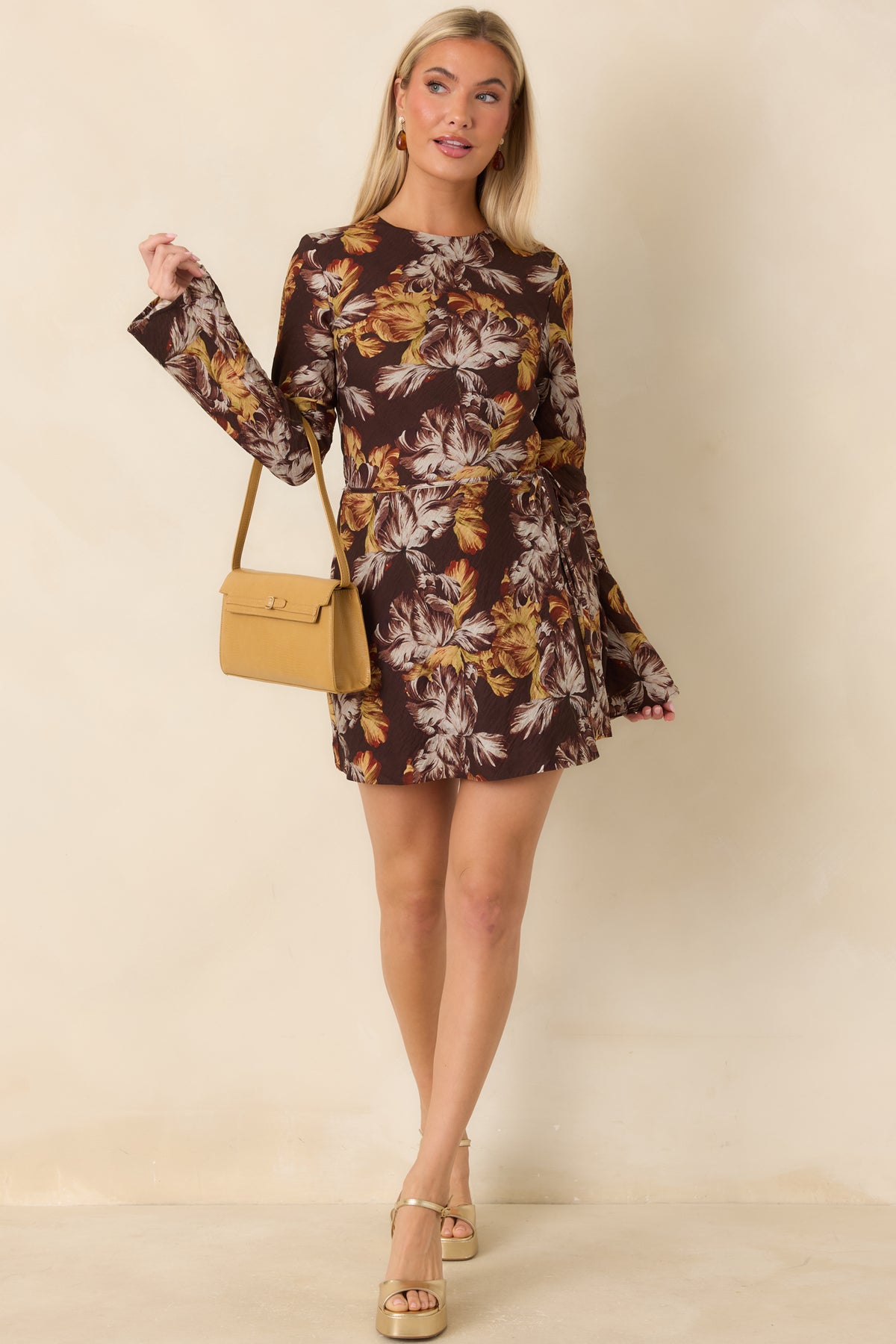 Floral mini dress featuring a fitted bodice, wrap-style skirt, and adjustable side tie in a rich brown botanical print.