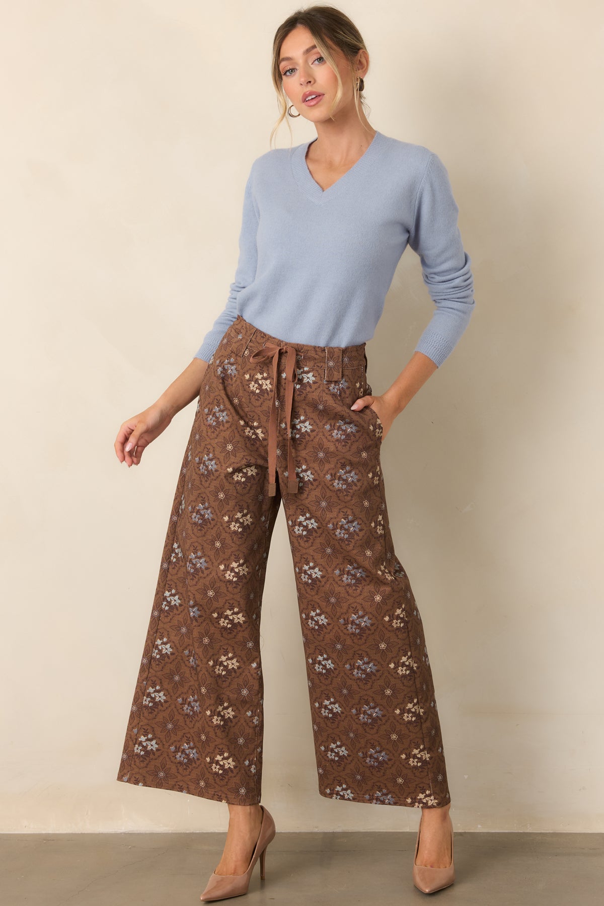 Brown floral cropped wide-leg pants with dusty blue, mauve, and cream medallions and a drawstring waistband.