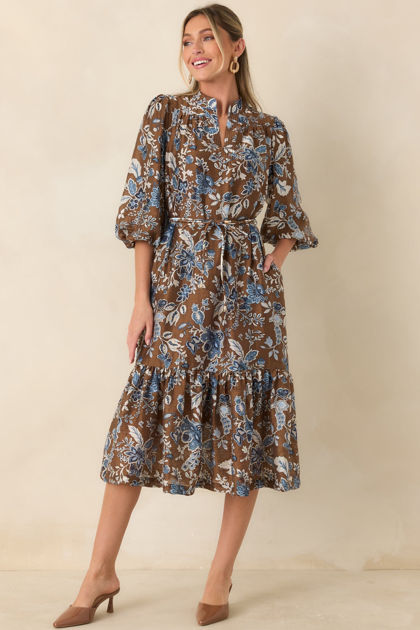 Soft fabric midi dress featuring a warm brown floral design, removable belt, gathered skirt, and elegant ruffle hem.