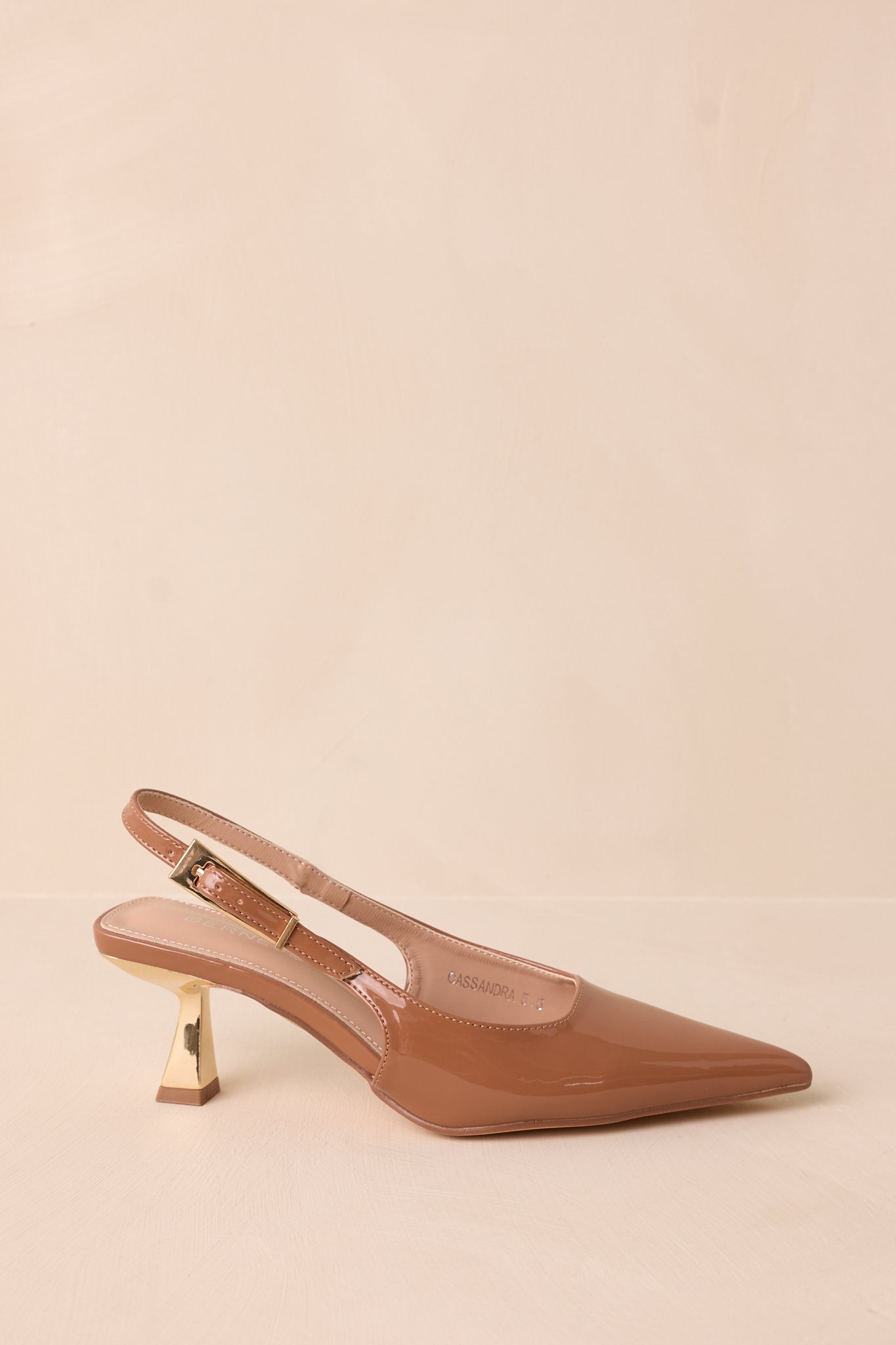 Angled view of the brown heels emphasizing the patent finish, pointed toe, and elegant silhouette.