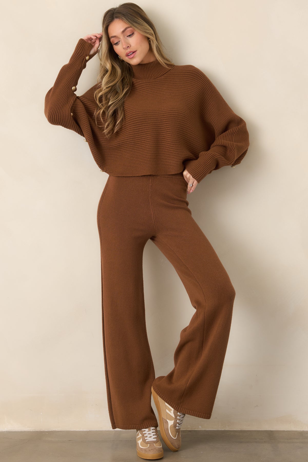Brown knit pants featuring a high-rise elastic waistband, smooth fit through the hips, relaxed wide legs, and textured ribbed side detailing.