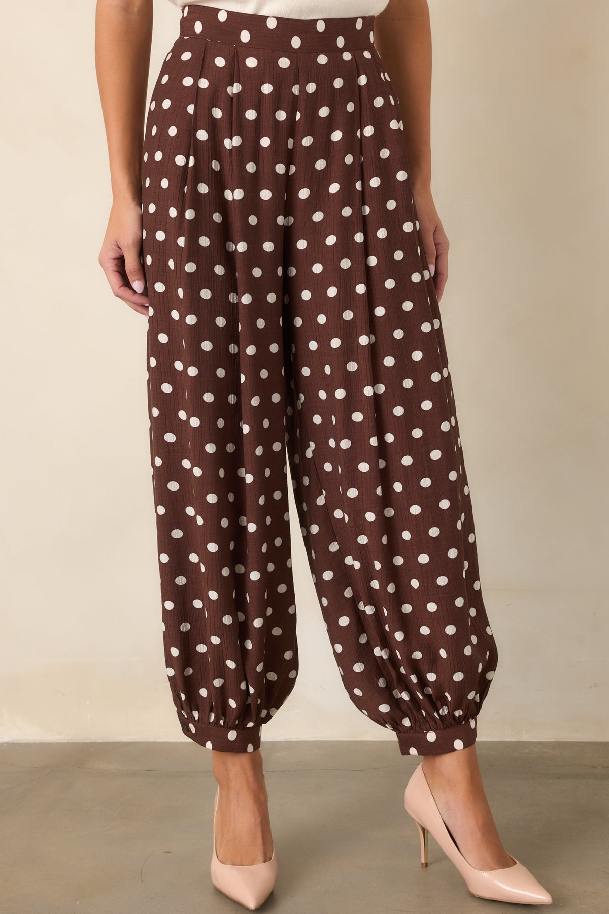Ivory polka dots pattern these brown pants with a relaxed balloon silhouette and defined waistband.