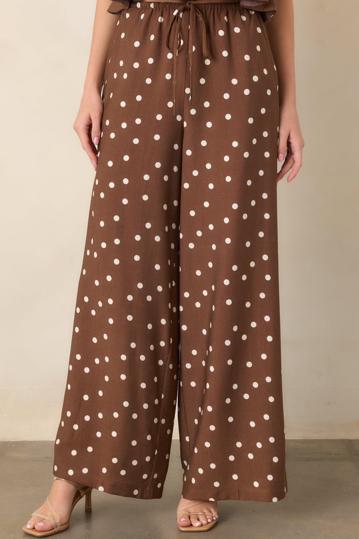 Brown and ivory polka dot pants shown in detail with a functional side pocket and softly flowing wide-leg construction.
