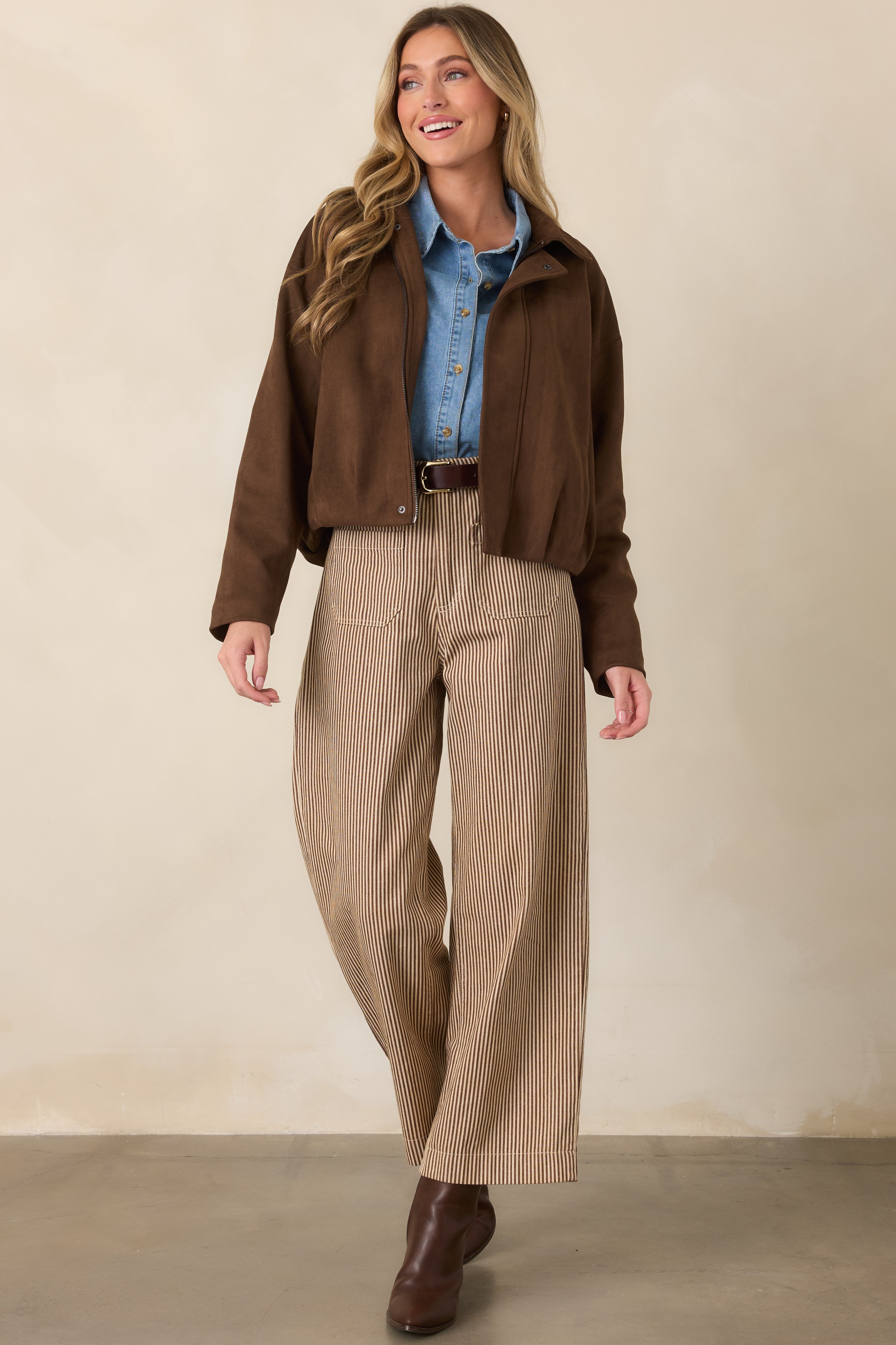 Brown and ivory striped pants with a high-rise waist, button and zip closure, front patch pockets, and a relaxed wide-leg silhouette with a cropped hem.