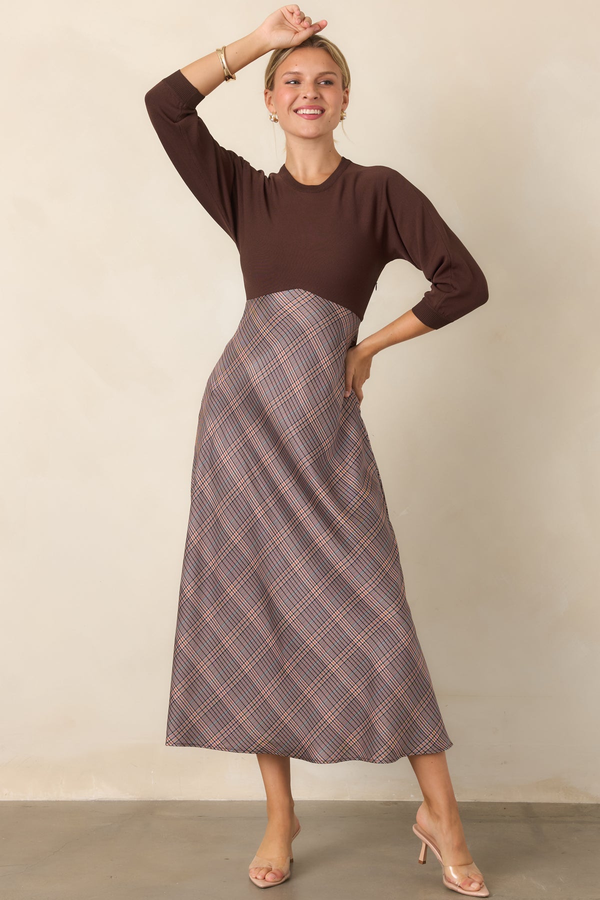 Brown knit dress with a fitted bodice, classic round neckline, and three-quarter sleeves.