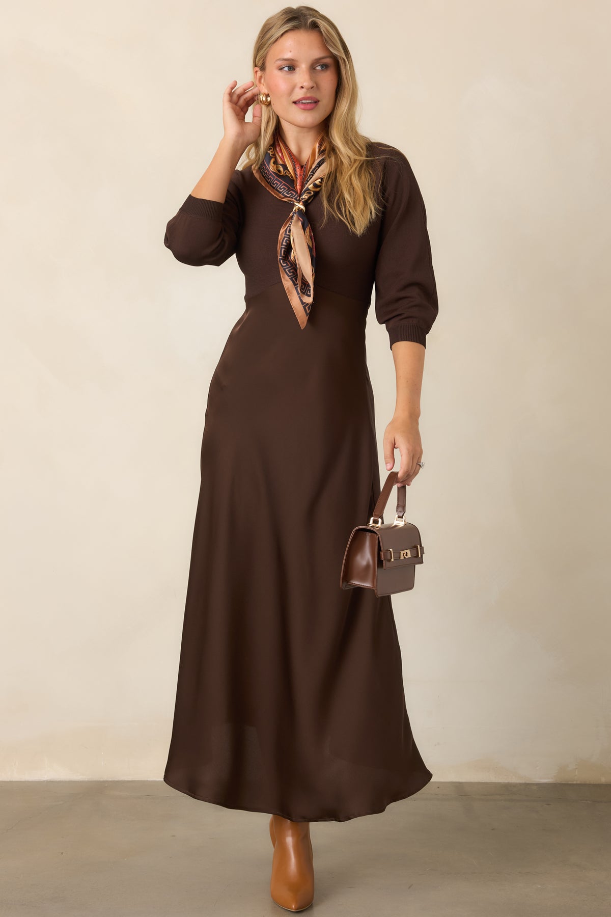 Coordinated brown dress with a round-neck knit top, three-quarter sleeves, defined waist, and elegant satin A-line midi skirt.