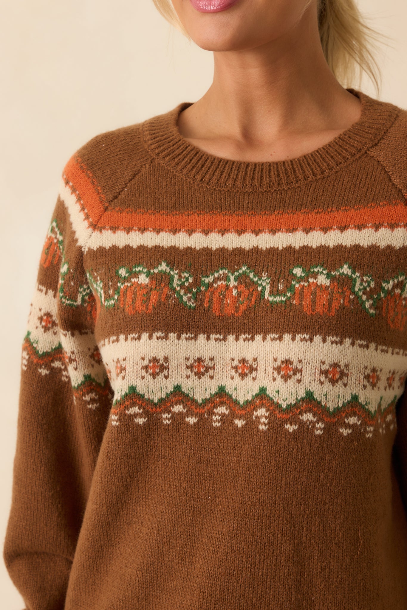 Close-up of brown knit sweater showcasing the multicolor pumpkin and floral fair isle pattern and ribbed knit texture.