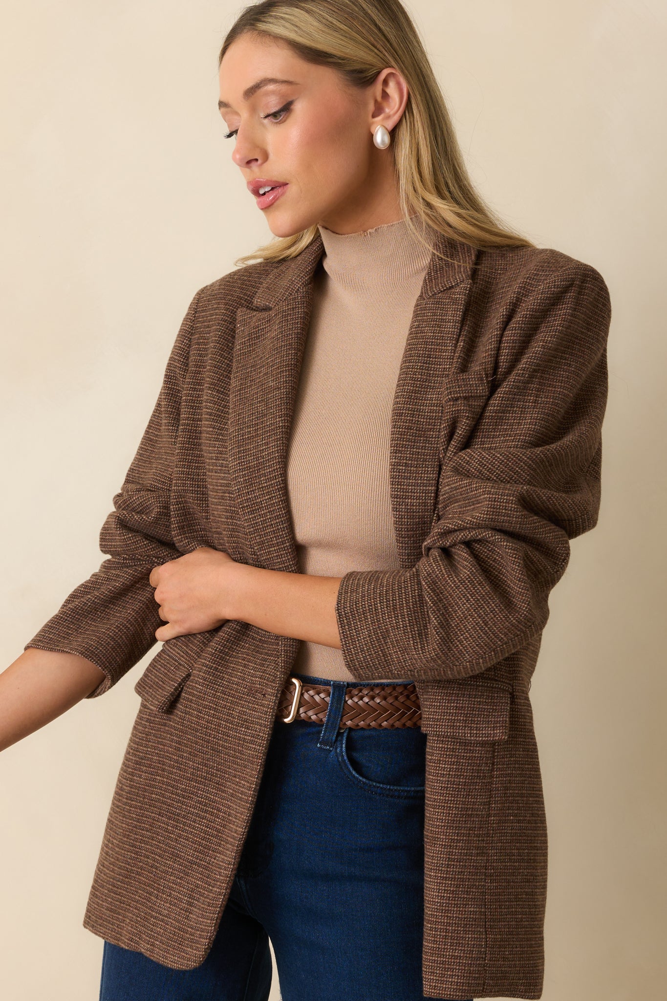 Brown blazer in micro-houndstooth fabric with a notched lapel, single-breasted front, and longline tailored silhouette.