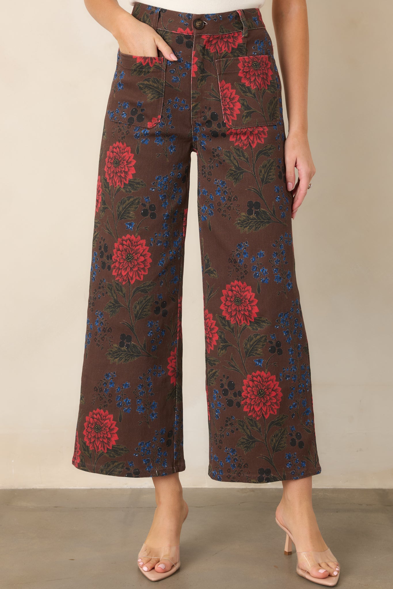 Close view of the high-rise pants highlighting the rich brown fabric and vivid red, blue, olive, and black floral pattern.