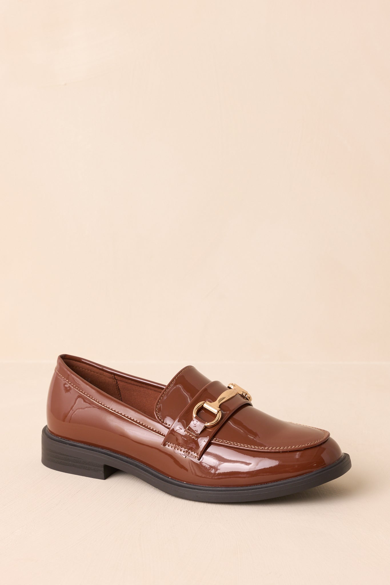 Brown patent loafer with almond toe and slip-on design.