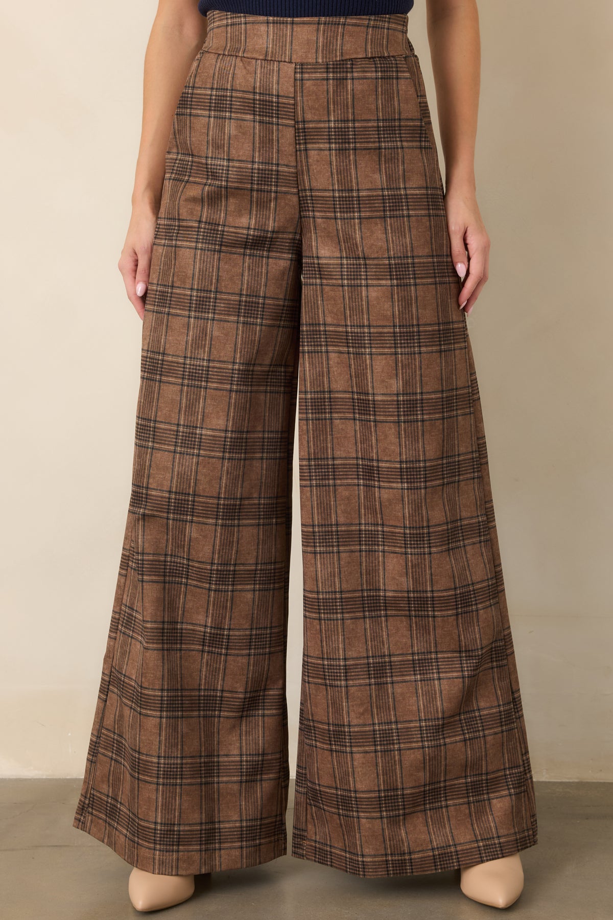 Brown plaid pants highlighting the high-rise waistband and flowing wide-leg silhouette with a touch of comfortable stretch.