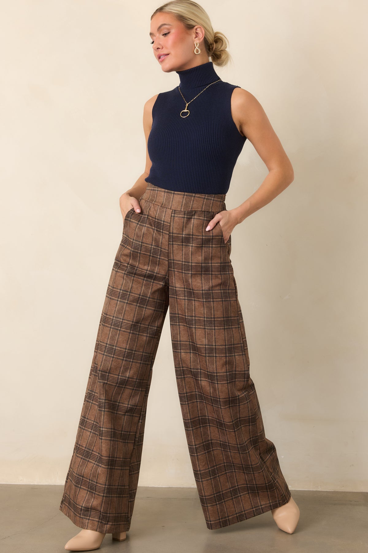 Brown plaid trousers showcasing a long, fluid wide-leg silhouette, high-rise waist, and softly structured construction.