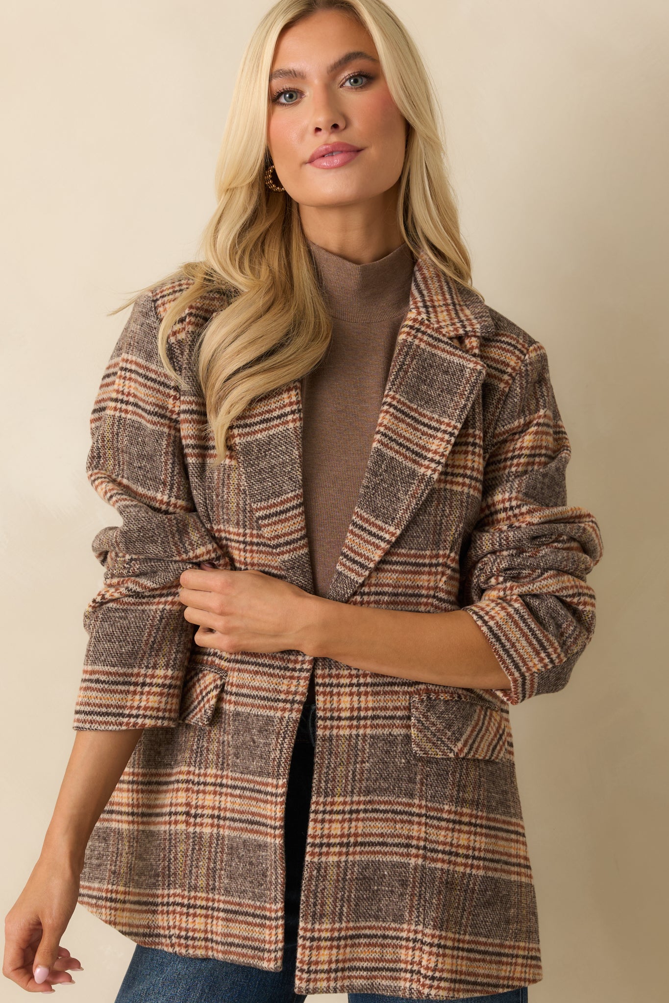 Brown plaid overcoat focused on the flap pockets and mid-length hem.