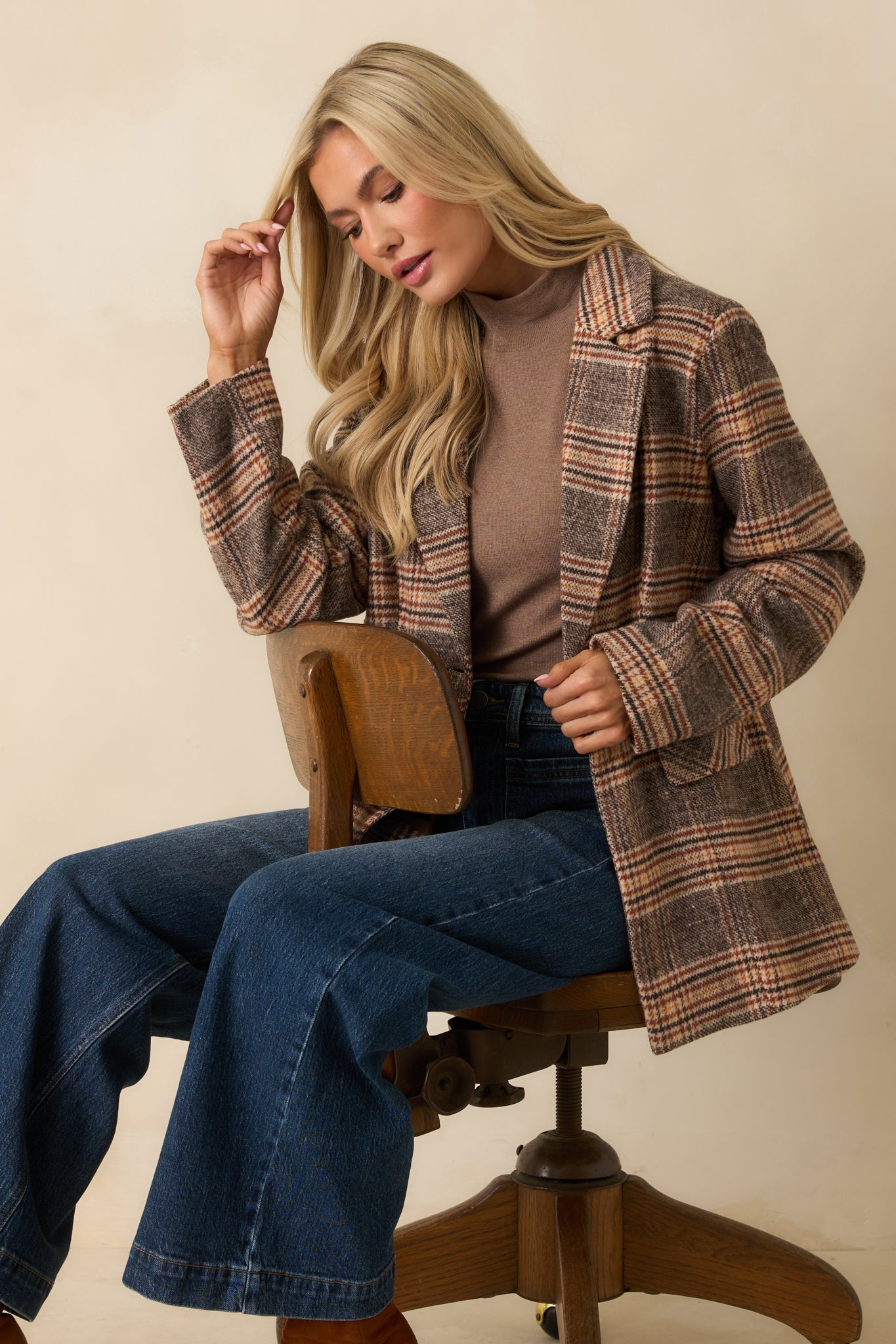 Brown plaid overcoat displayed front-facing, highlighting its relaxed fit, collared neckline, long sleeves, and flap pockets.