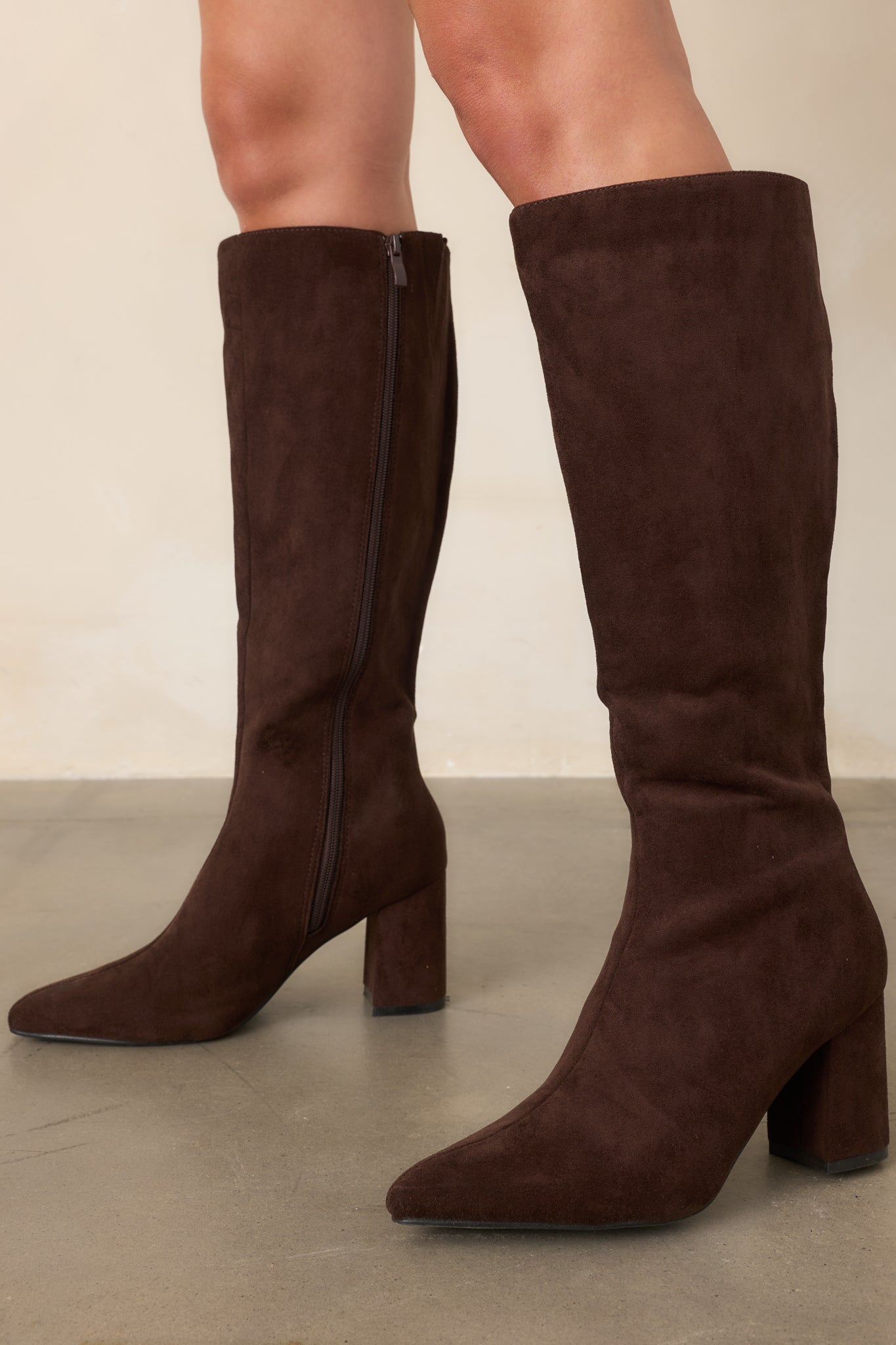 Close view of the streamlined pointed toes and smooth faux suede finish on the tall brown boots.