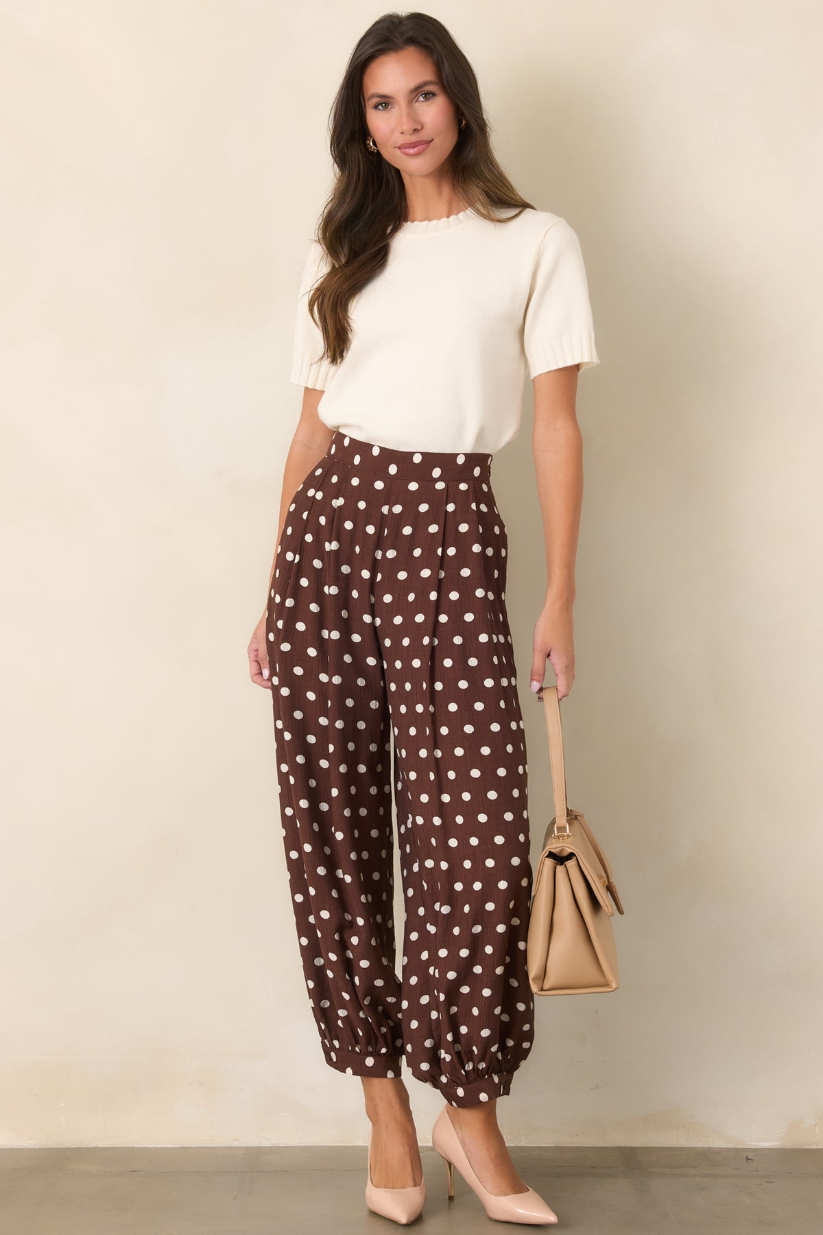 Brown polka dot pants featuring a defined waistband, roomy legs, and buttoned ankle cuffs.