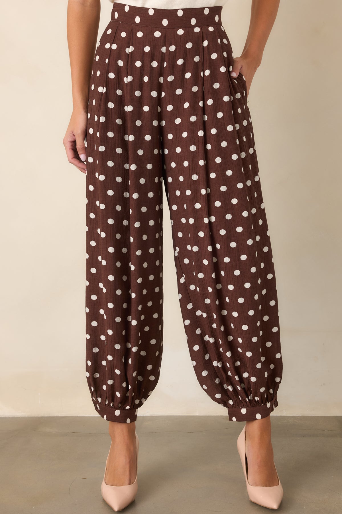 Voluminous brown polka dot pants with roomy legs gathered into buttoned ankle cuffs.