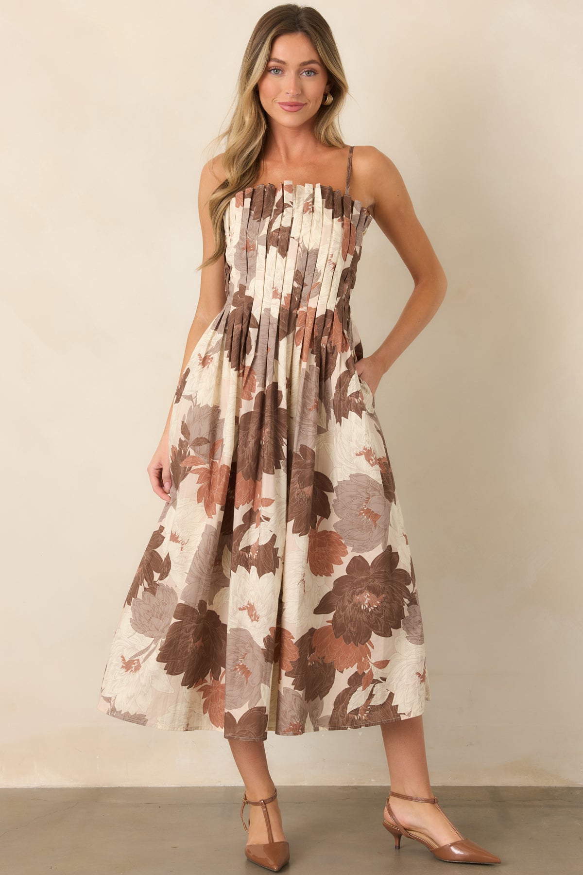 Oversized floral cotton dress with brown, rust, taupe, and ivory tones, textured pleated bodice, adjustable straps, and a flowing midi-length A-line skirt.