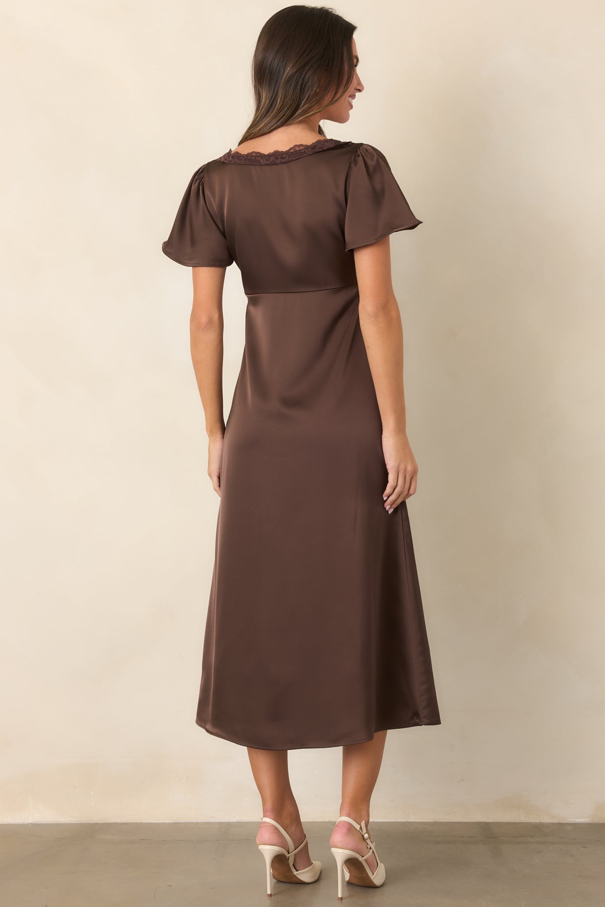 Brown satin midi dress showcasing the softly gathered bodice, flowing skirt, and flutter sleeves from the rear.