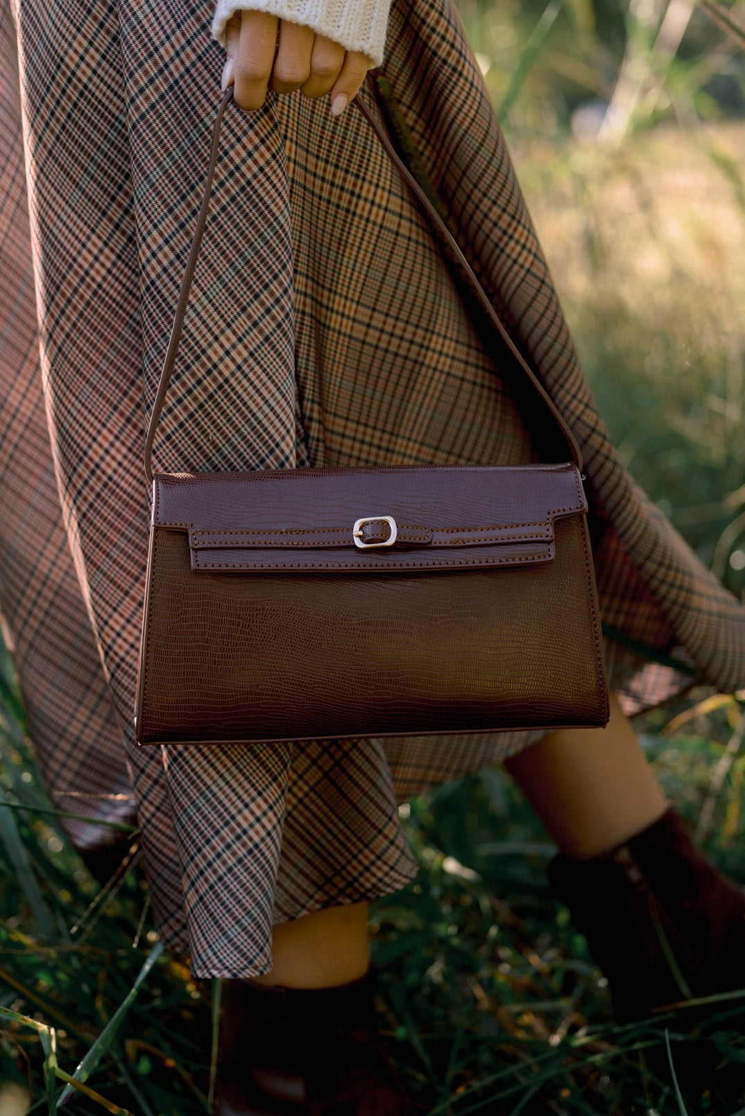 Brown shoulder bag featuring a slim strap and gold-tone buckle accent on the front flap.