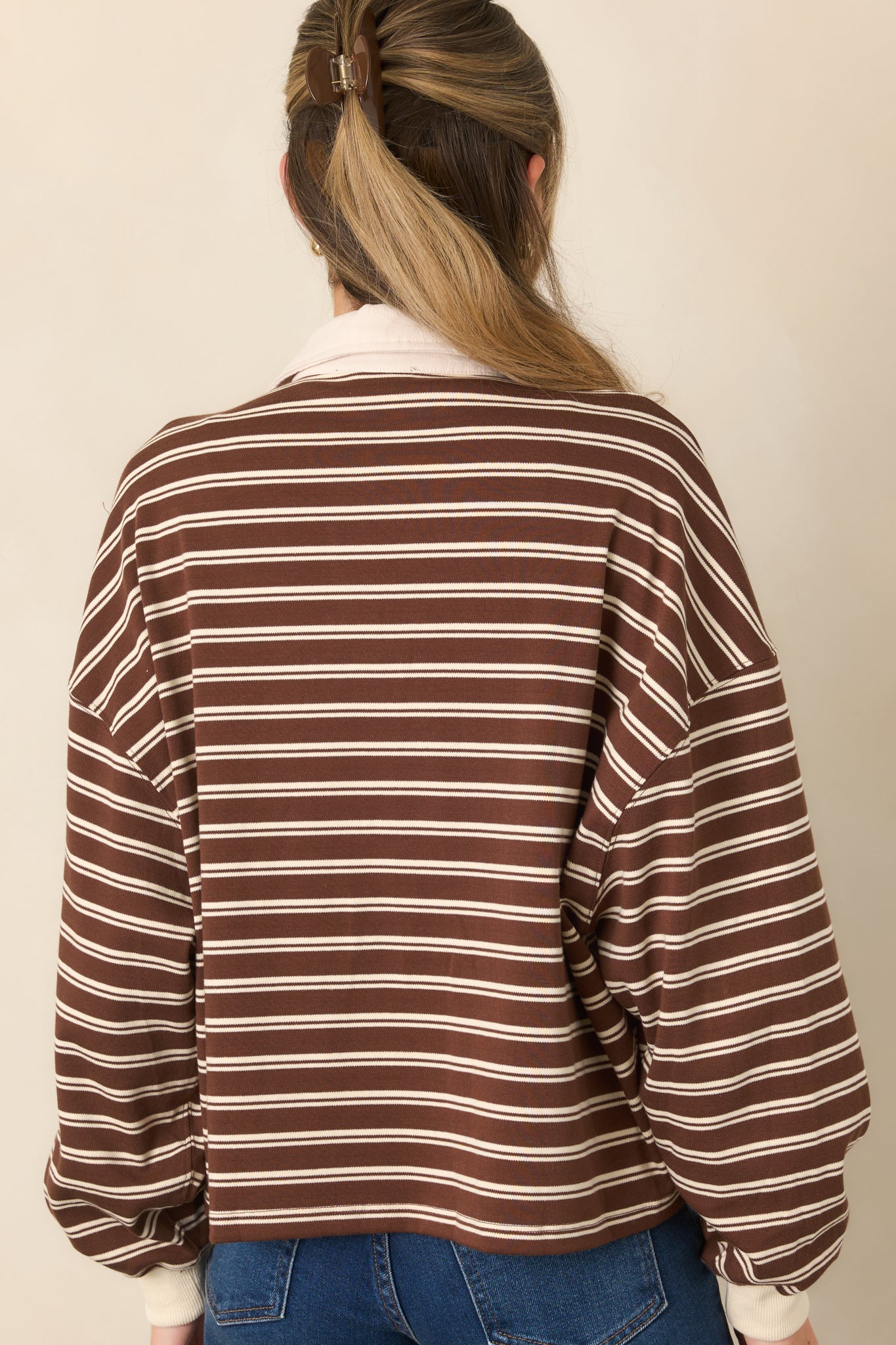 Rear view of the brown striped knit top featuring a loose boxy silhouette, dropped shoulders, and long sleeves.