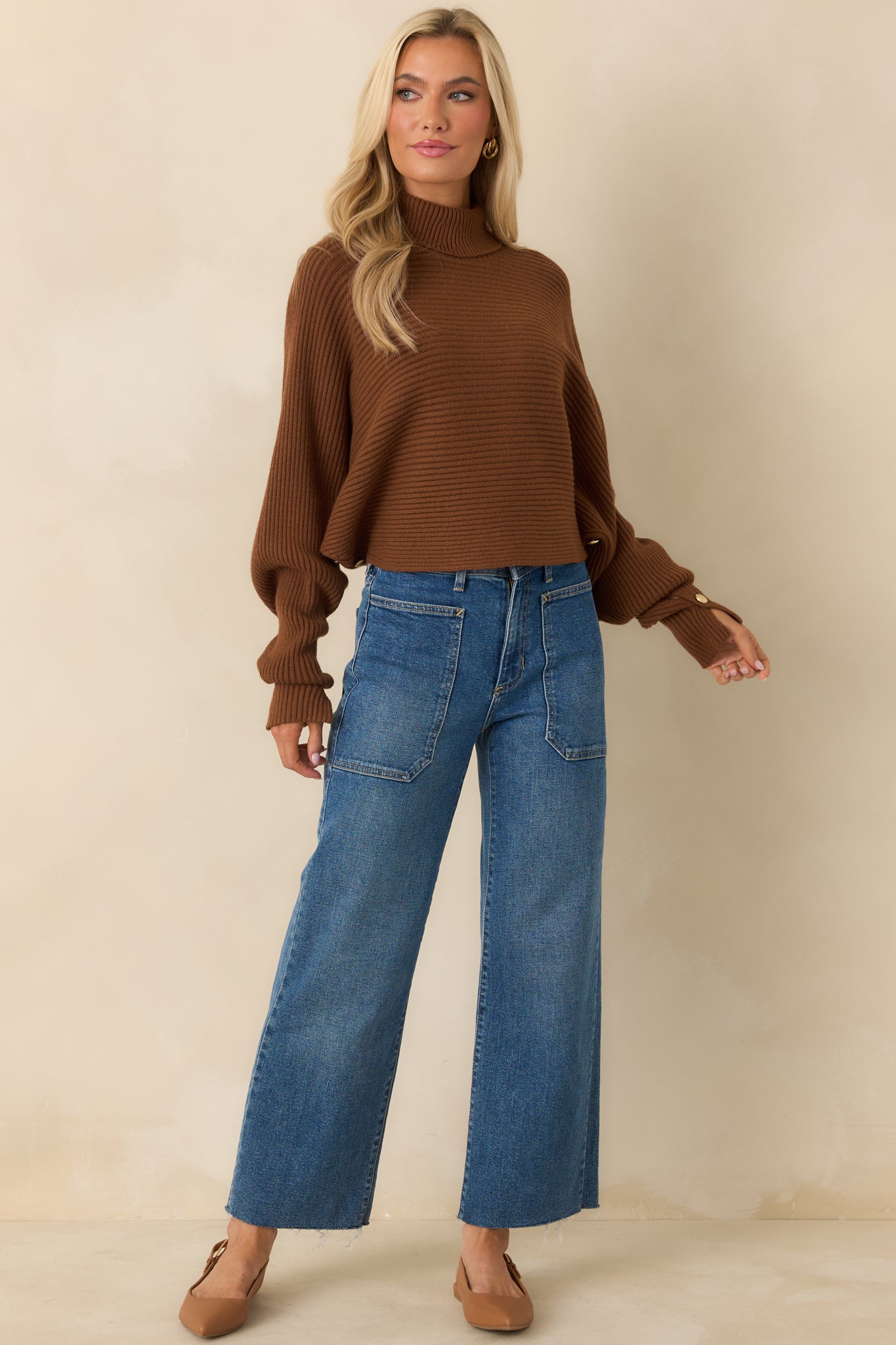 Ribbed brown sweater showcasing draped batwing sleeves and cropped hemline.