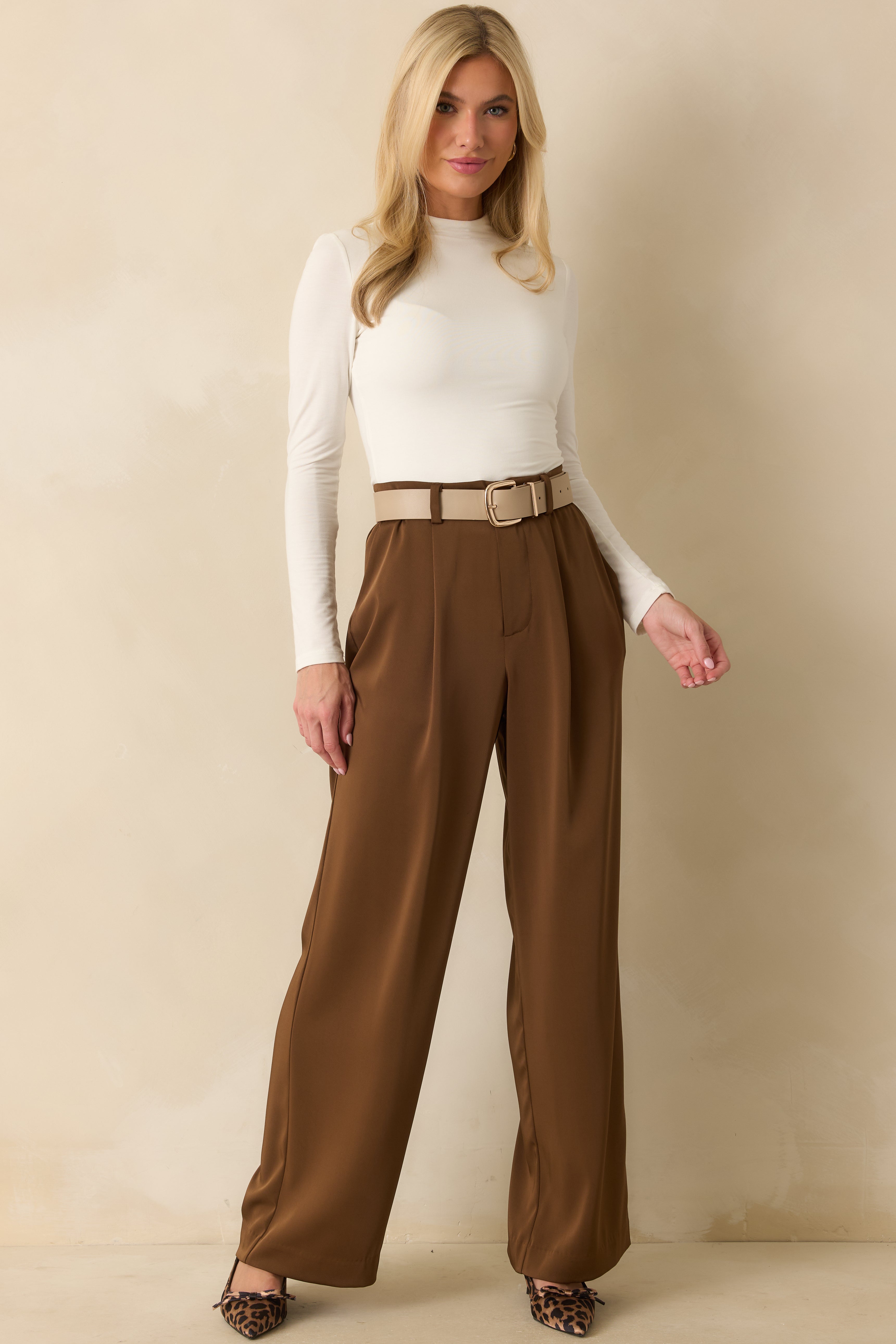 Angled front view of the brown trousers highlighting the structured shape and clean front design.