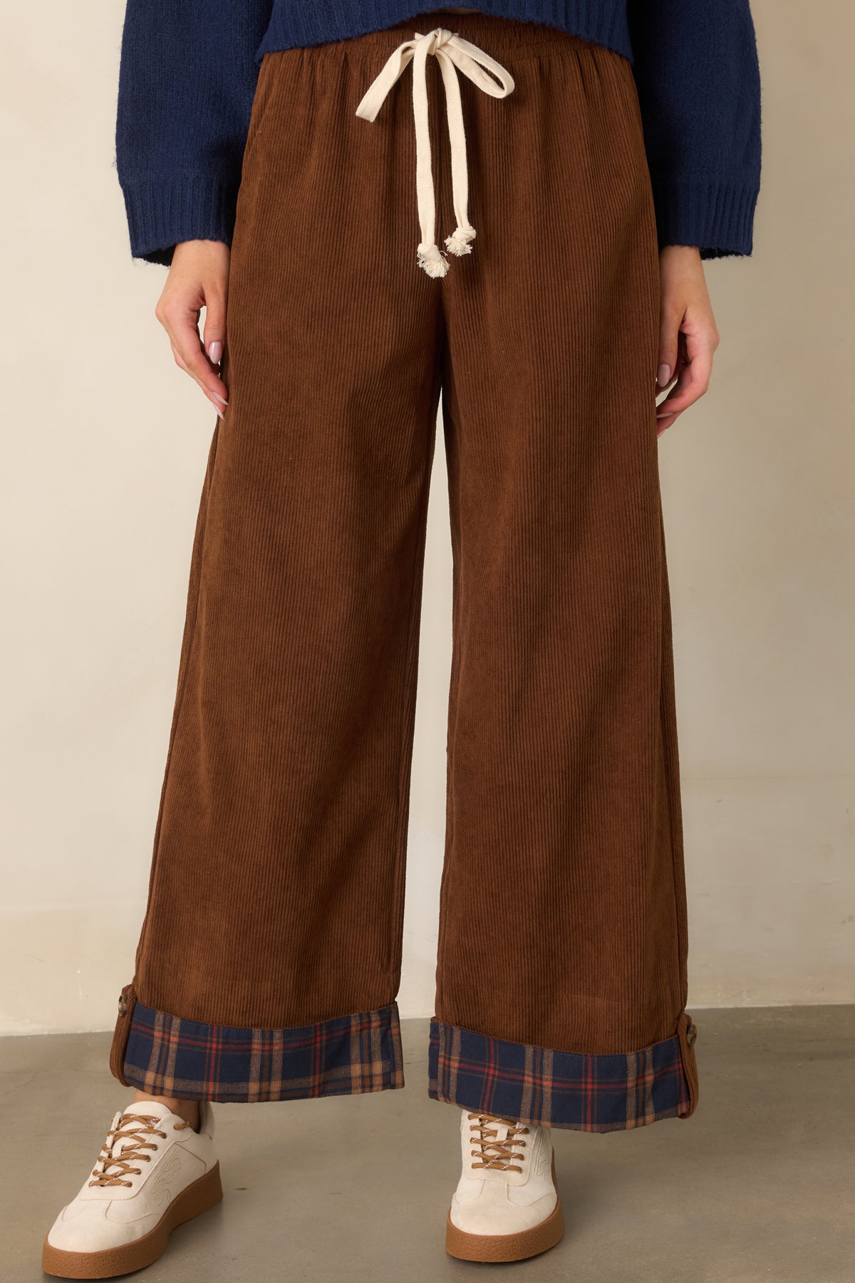 Wide-leg brown pants showcase the navy plaid cuffs and softly gathered drawstring waistband.