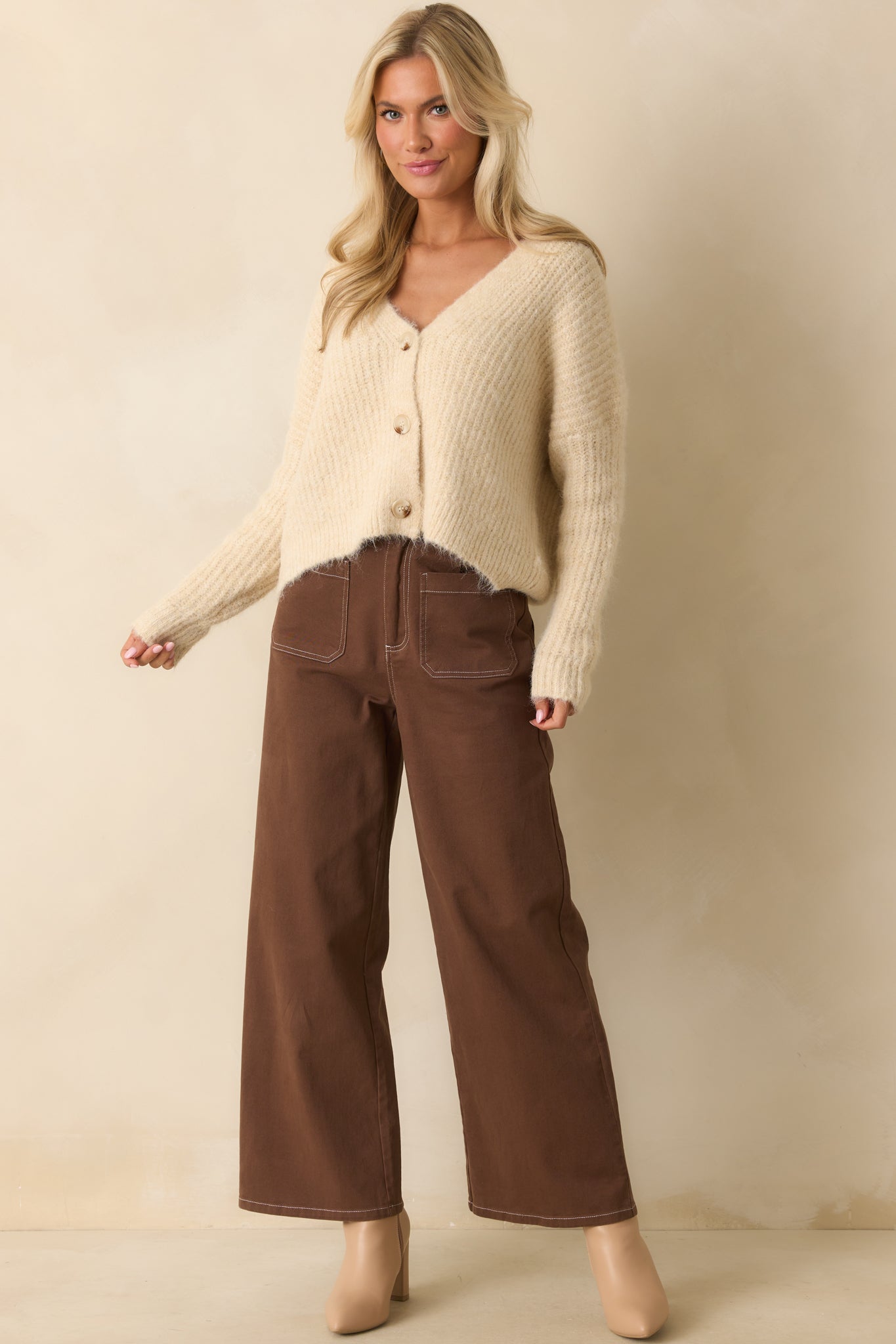 Brown wide-leg pants highlighting ivory contrast topstitching along seams and full front fit.