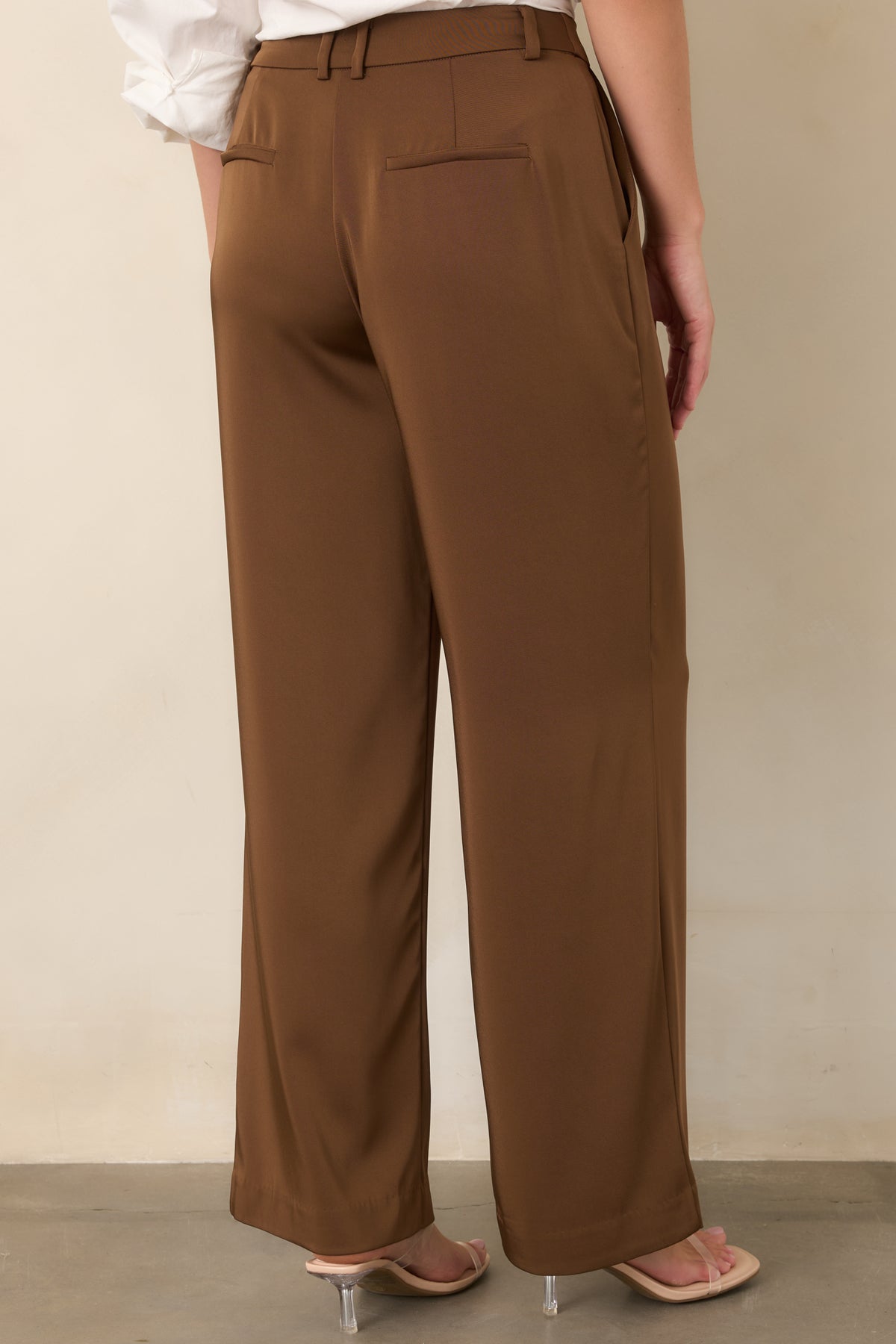 Rear view of brown wide-leg trousers with faux welt pockets and tailored waist.