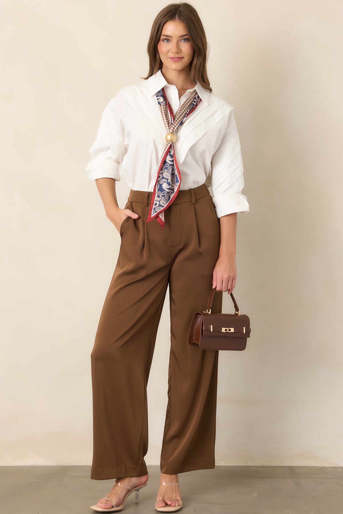Brown wide-leg trousers with high-rise waist, front pleats, and side pockets.