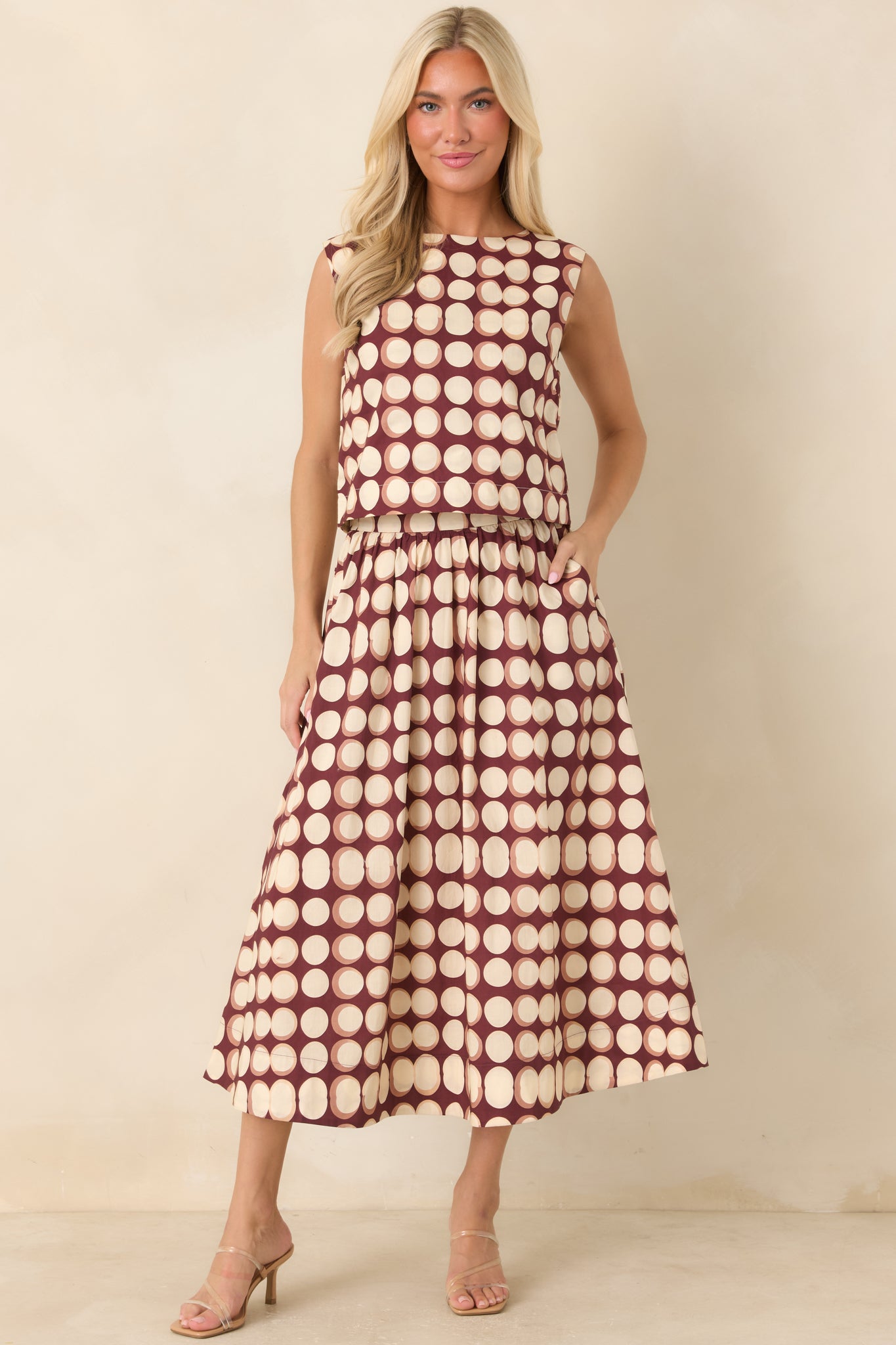 Cropped cotton top featuring a burgundy background with ivory and muted tan abstract dots, a boat neckline, and sleeveless silhouette.