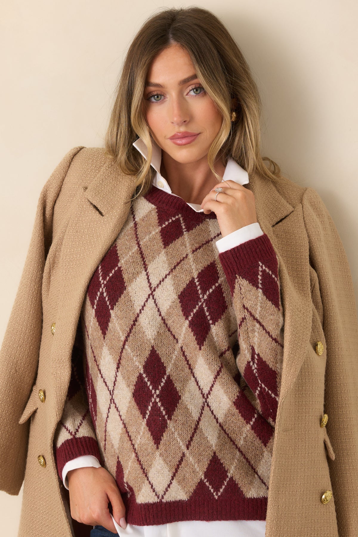 Burgundy knit fabric displays layered argyle diamonds in complementary neutral shades across the sweater.