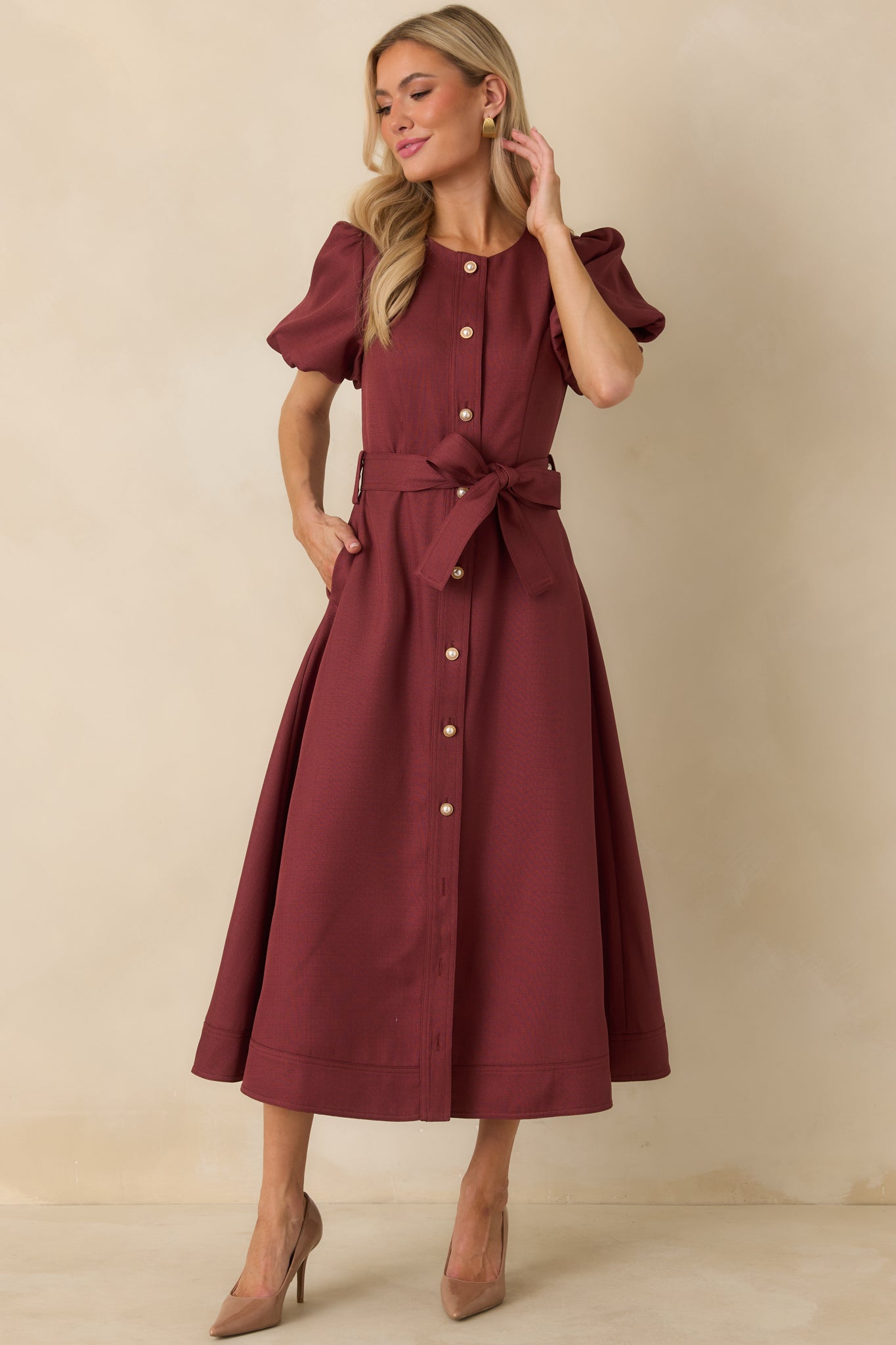 Burgundy belted midi dress showcasing side pockets, pearl and gold buttons, short puff sleeves, and an A-line silhouette.