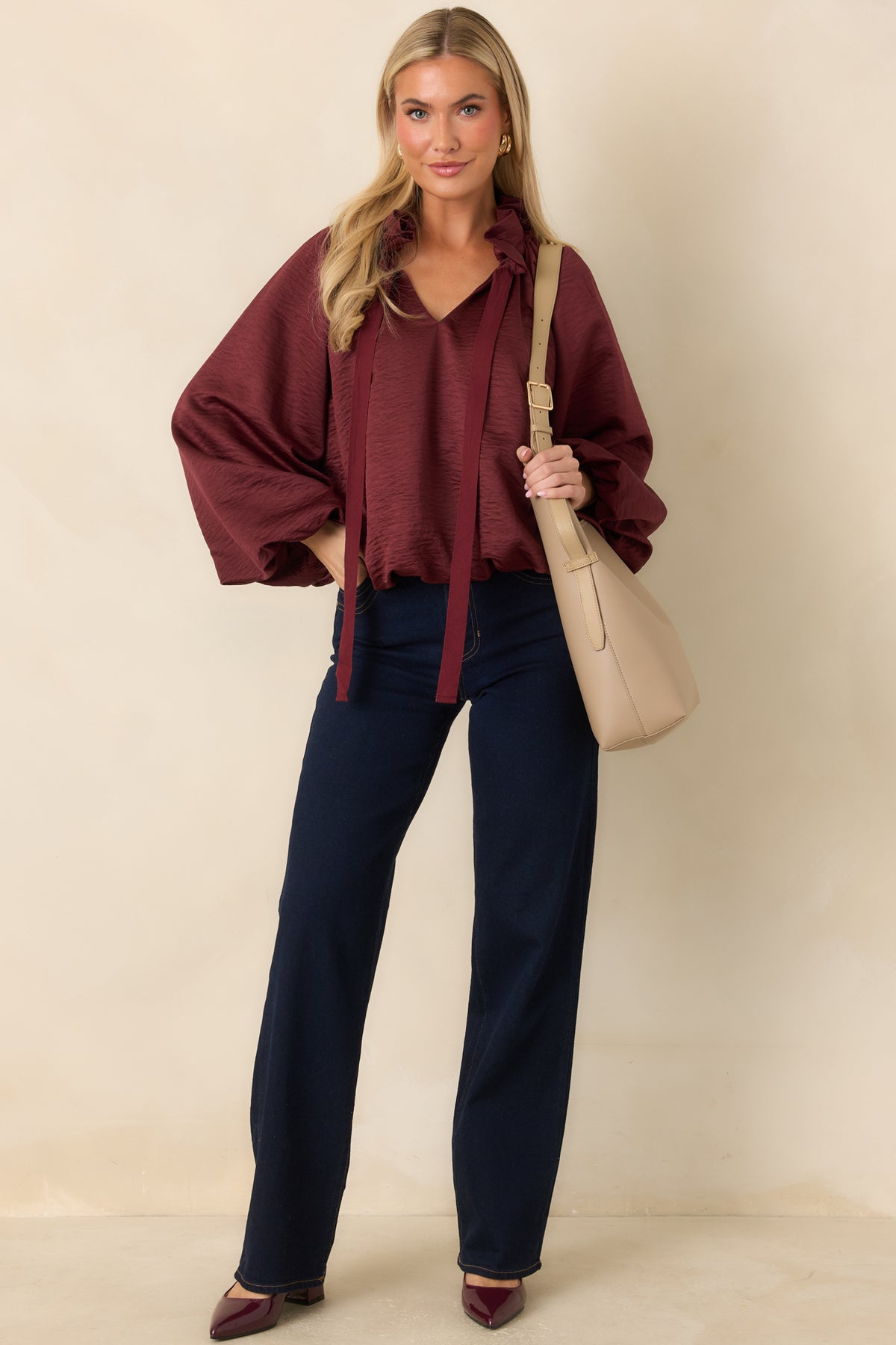 Rich burgundy blouse featuring a split V-neck, long neckline ties, voluminous sleeves, and an elasticized bubble hem.