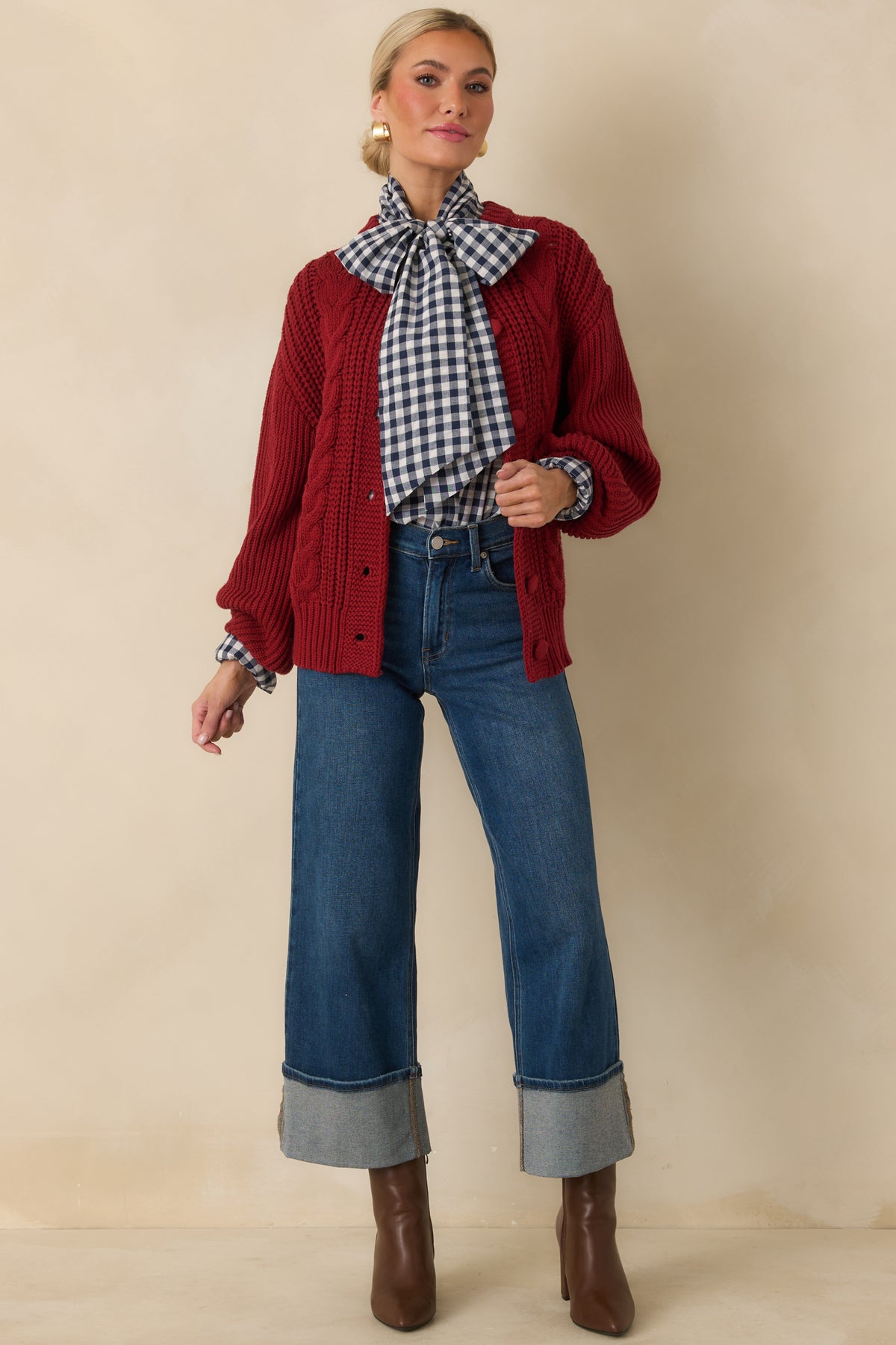 Burgundy cable-knit cardigan with a ribbed hem, fitted cuffs, and tonal buttons along the front.