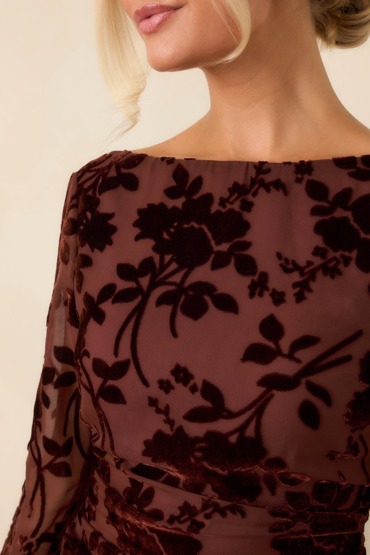 Close-up of the burgundy dress’s raised floral velvet burnout texture layered over sheer mesh, with delicate ruching nearby.