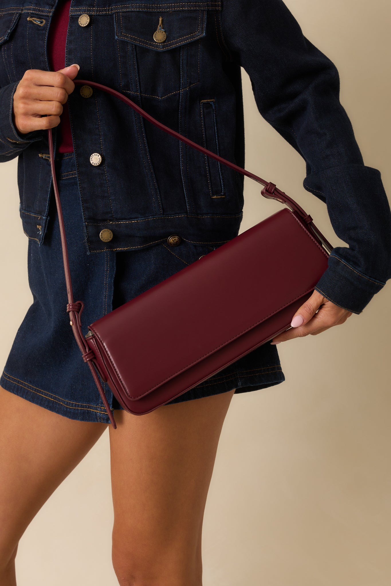 A full view of the burgundy faux leather baguette-style handbag with a rectangular body and fold-over flap.