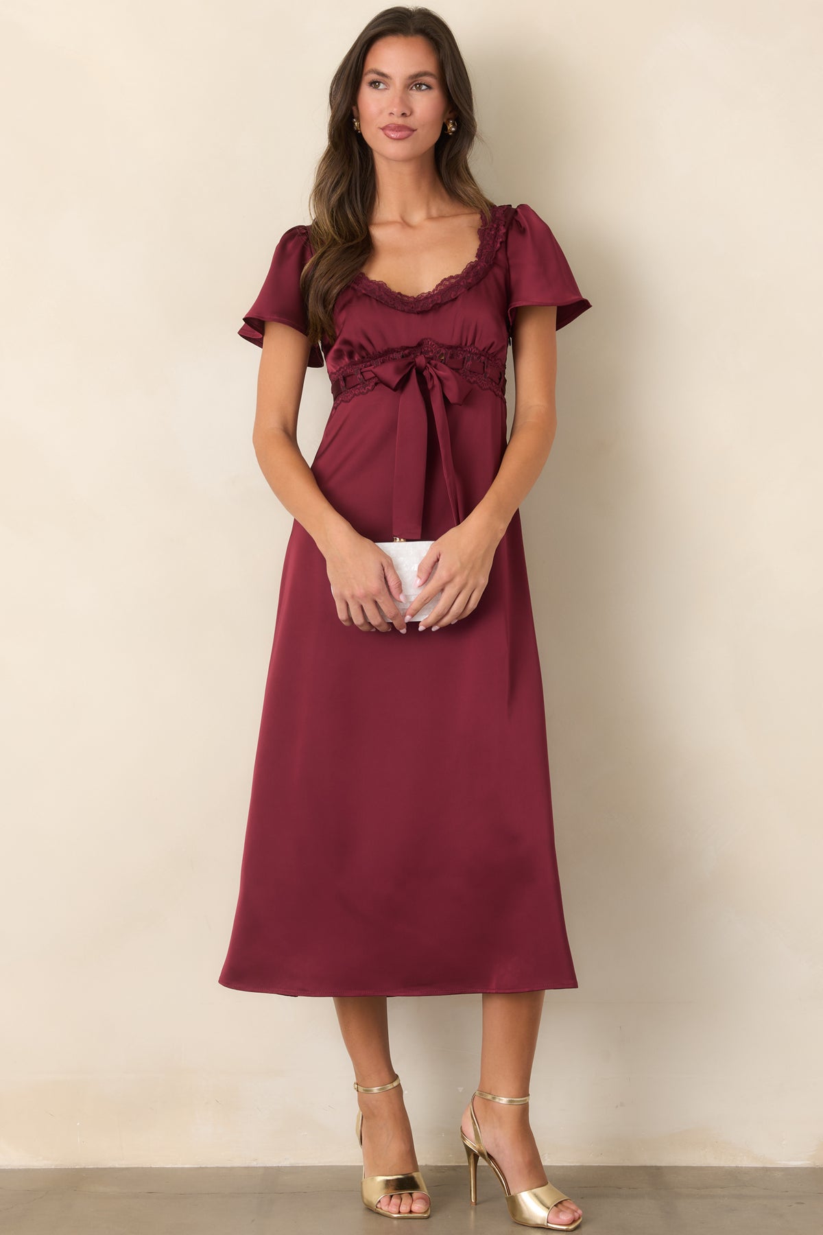 Romantic burgundy midi dress showcasing a gathered bodice, short flutter sleeves, and a gently flared skirt.