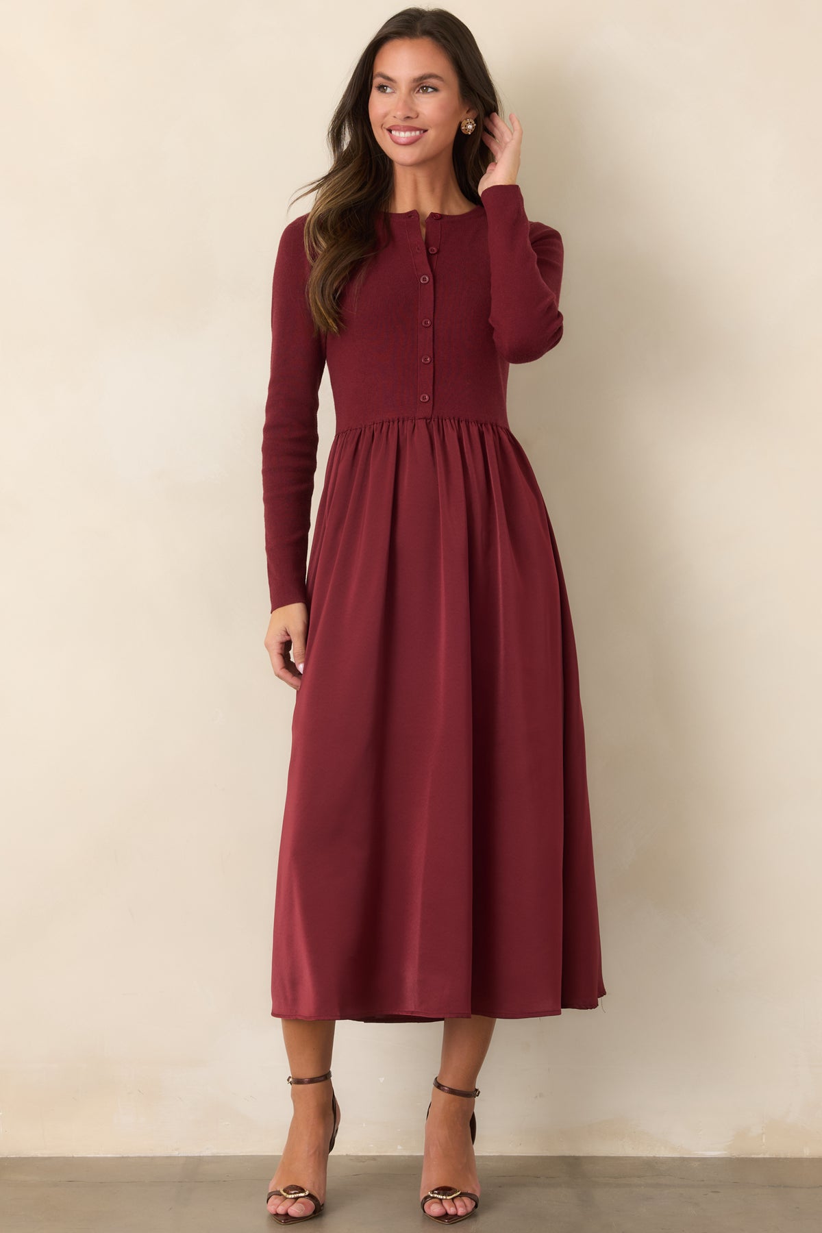 Burgundy dress combining a neat knit bodice with a flowing satin midi skirt and defined waist.