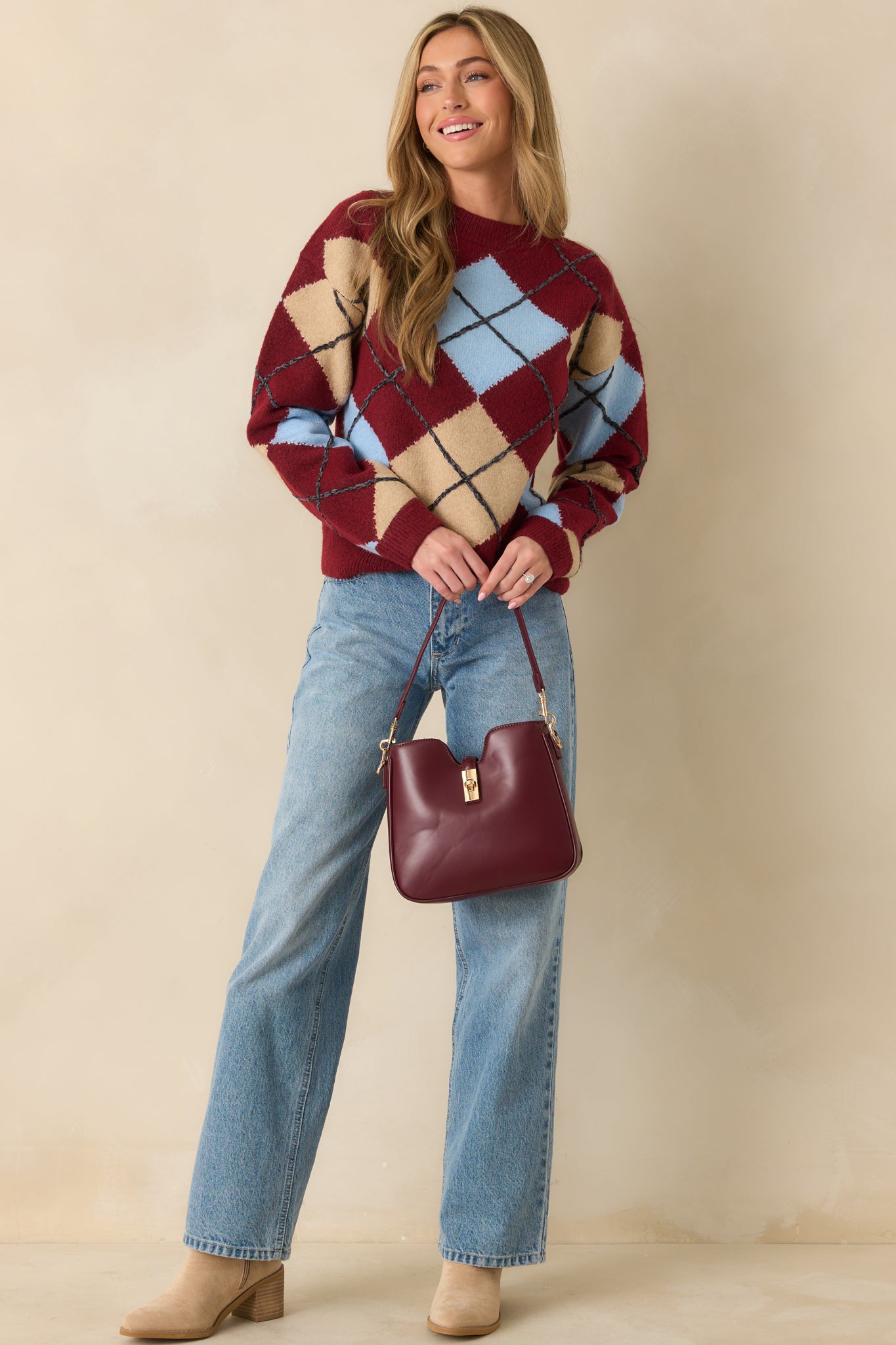 Burgundy knit sweater with multicolor argyle pattern across front and sleeves.