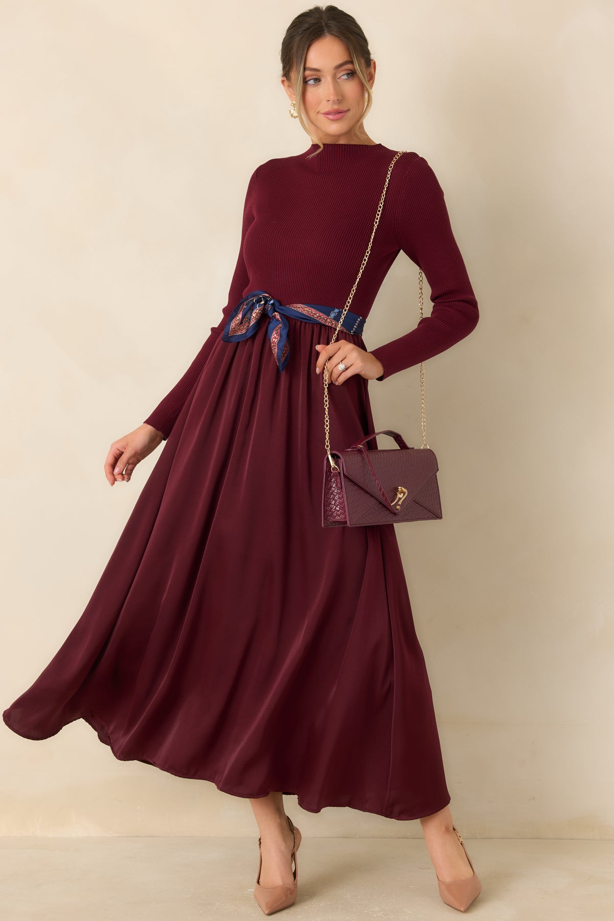 Long-sleeve burgundy dress with a close-fitting knit top and a gently flared satin skirt.