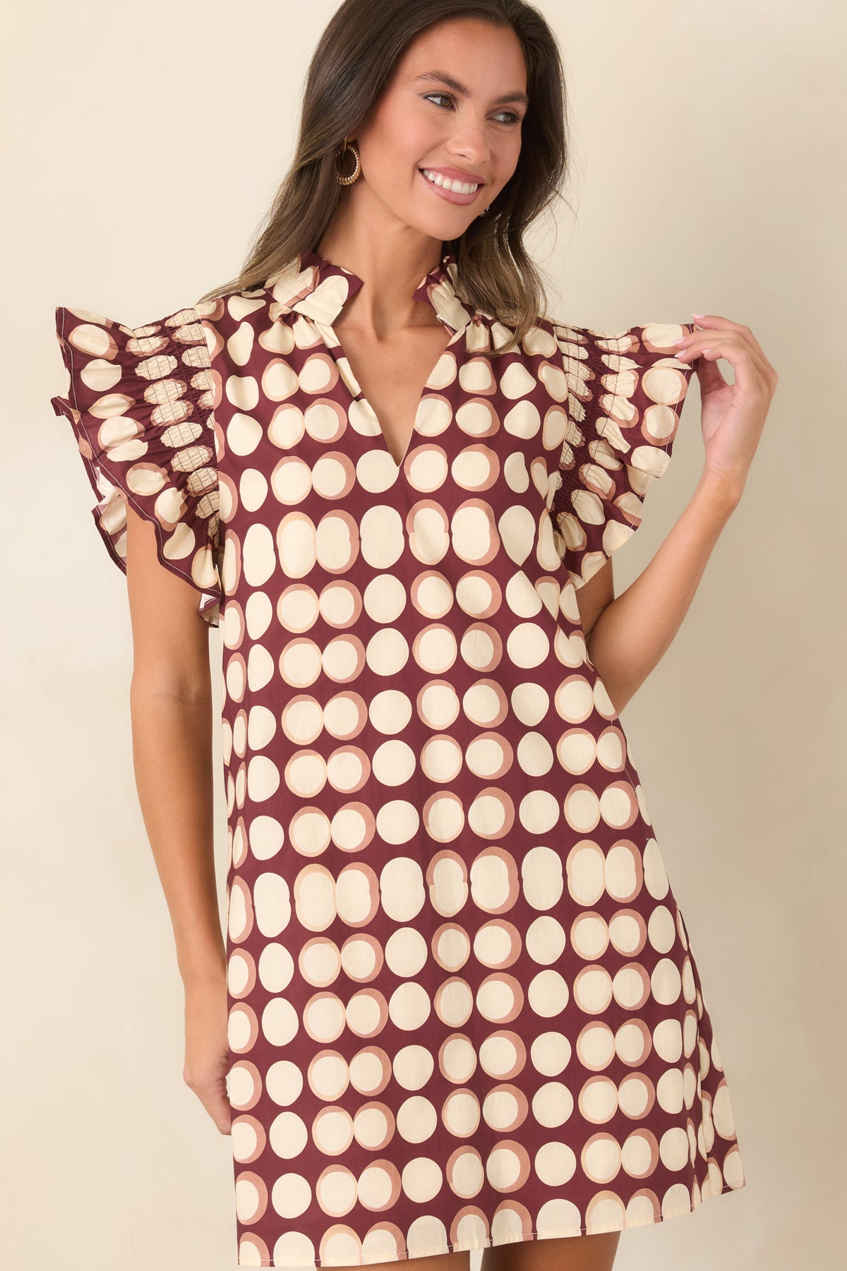 Burgundy cotton dress highlighting the oversized ivory dot print, ruffled collar, split neckline, and softly gathered sleeves.